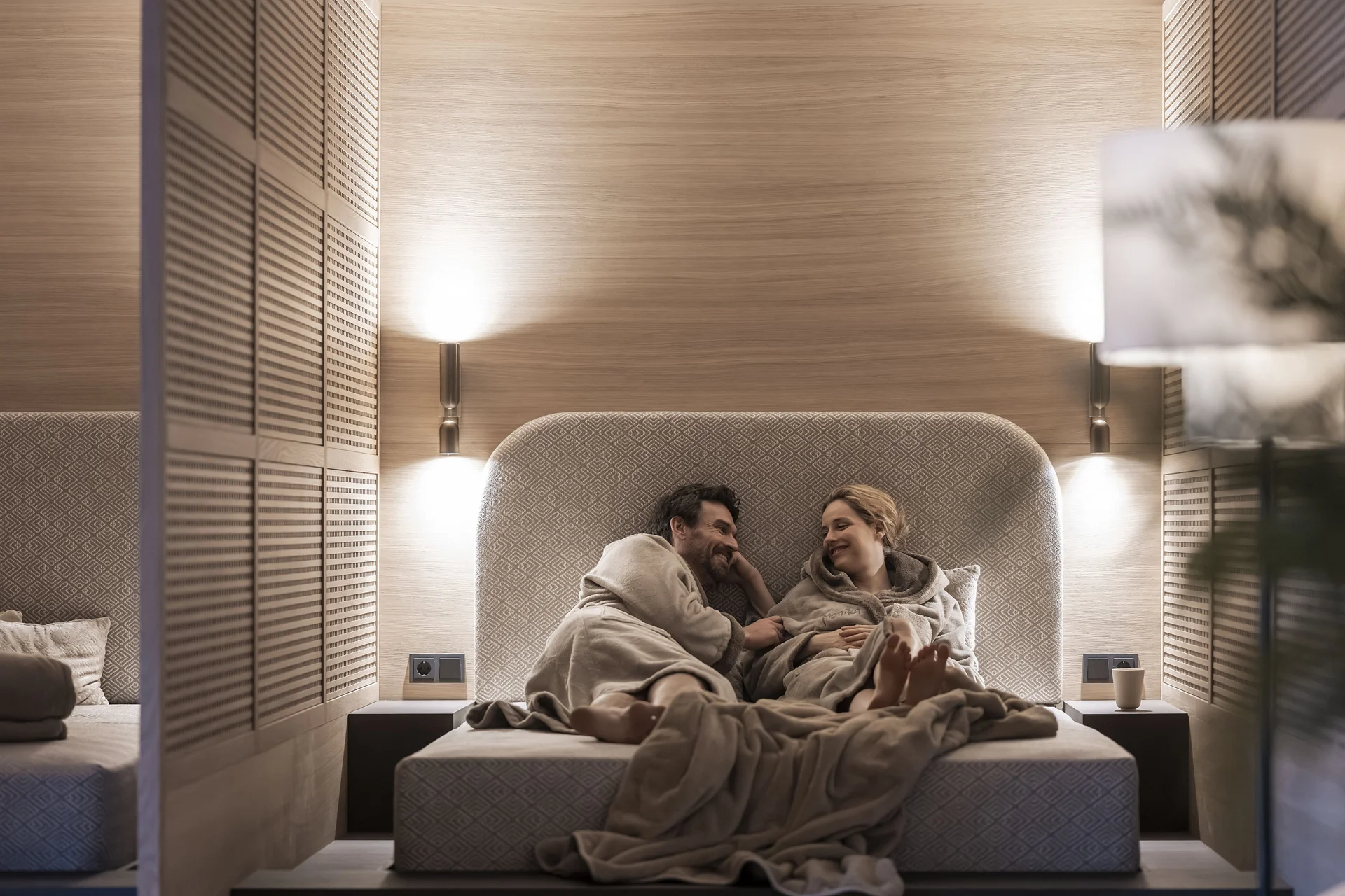 Paar entspannt in Bademänteln auf einem Bett in einem modernen Schlafzimmer