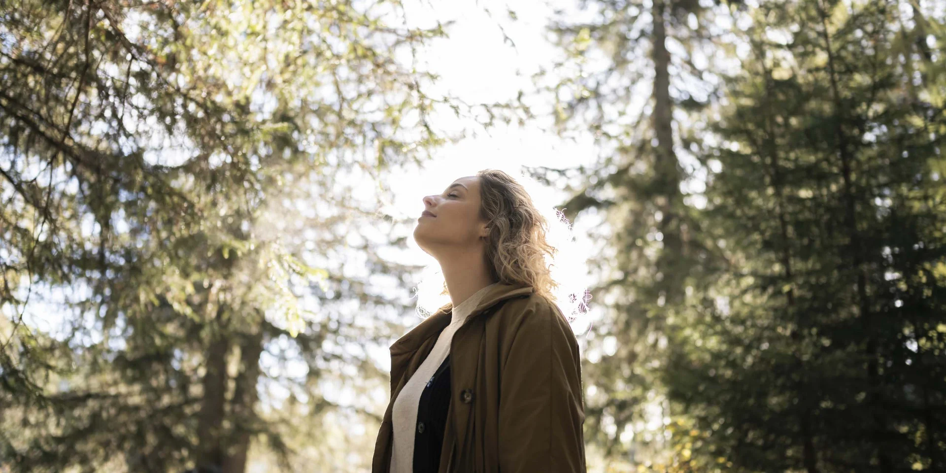 Donna che gode della natura nel bosco alla luce del sole