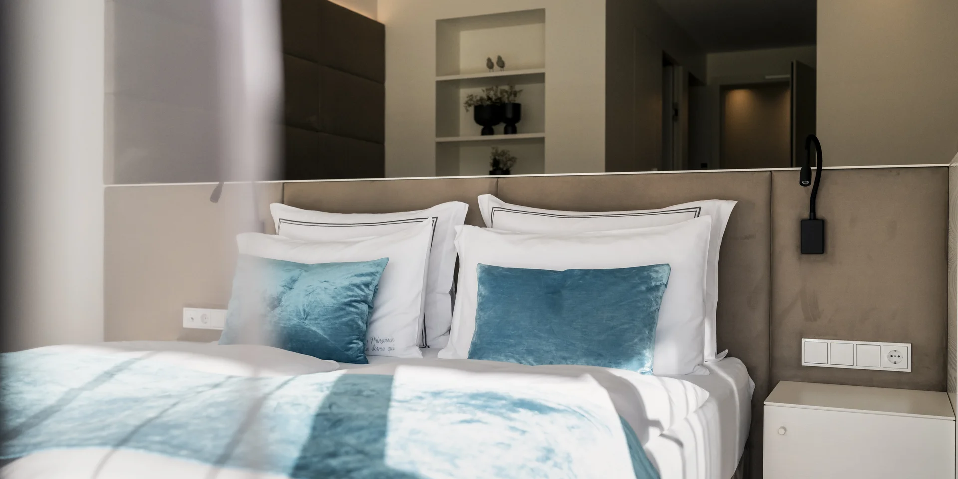 Modernes Schlafzimmer mit weißen und blauen Kissen und Decken
