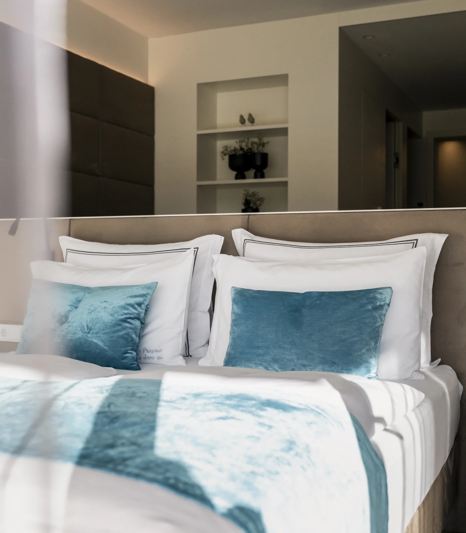 Modern bedroom with white and blue pillows and blankets