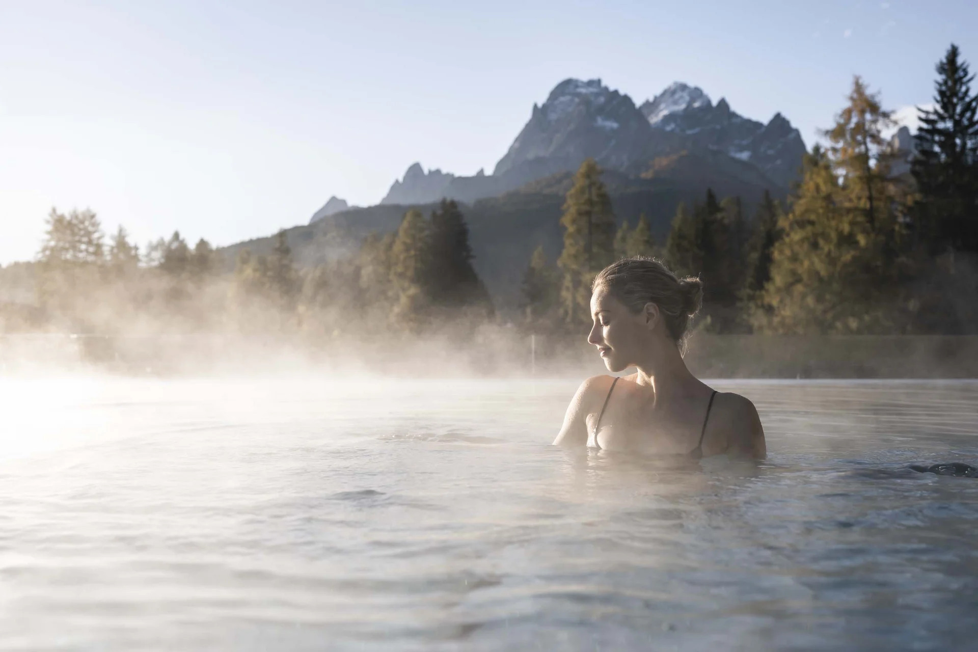 Frau entspannt im heißen Thermalbad mit Bergpanorama im Hintergrund