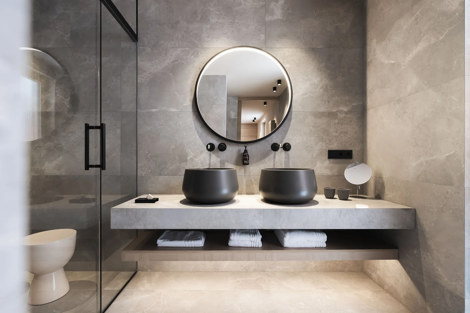 Modernes Badezimmer mit zwei schwarzen Waschbecken und ovalem Spiegel