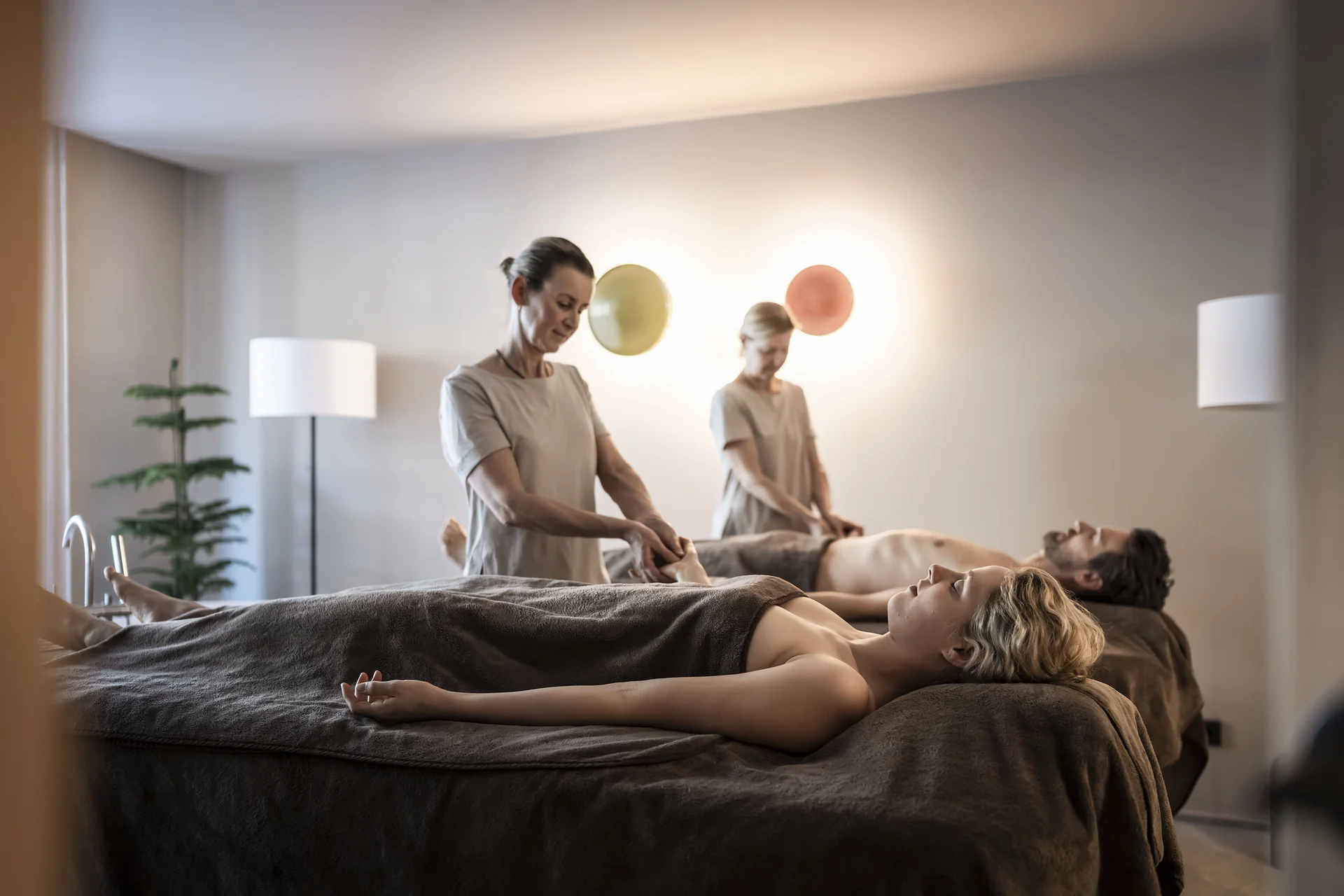 Coppia che riceve massaggio di coppia in spa su lettini con asciugamani marroni