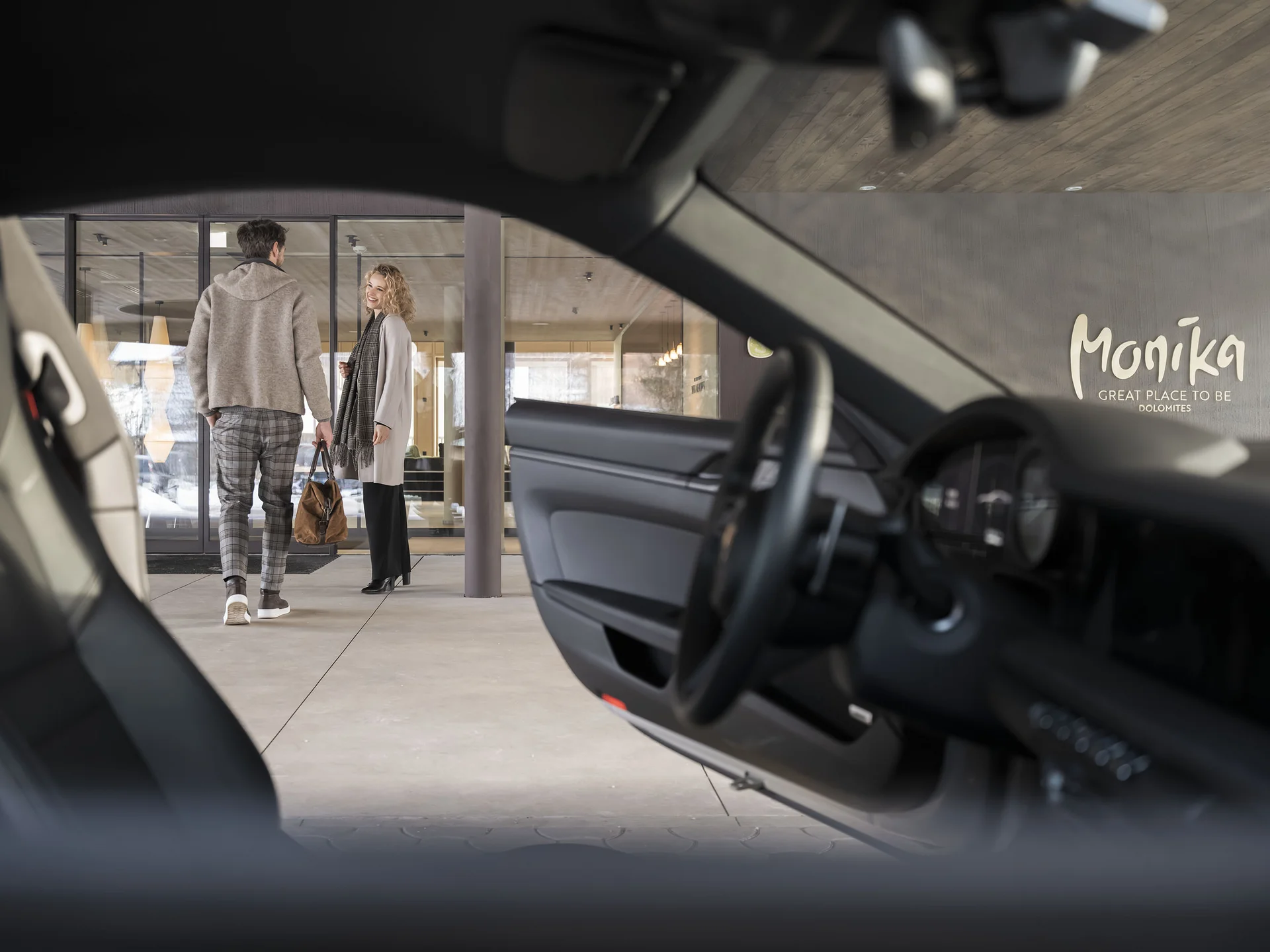 Vista attraverso un'auto su due persone davanti a un edificio con logo Monika