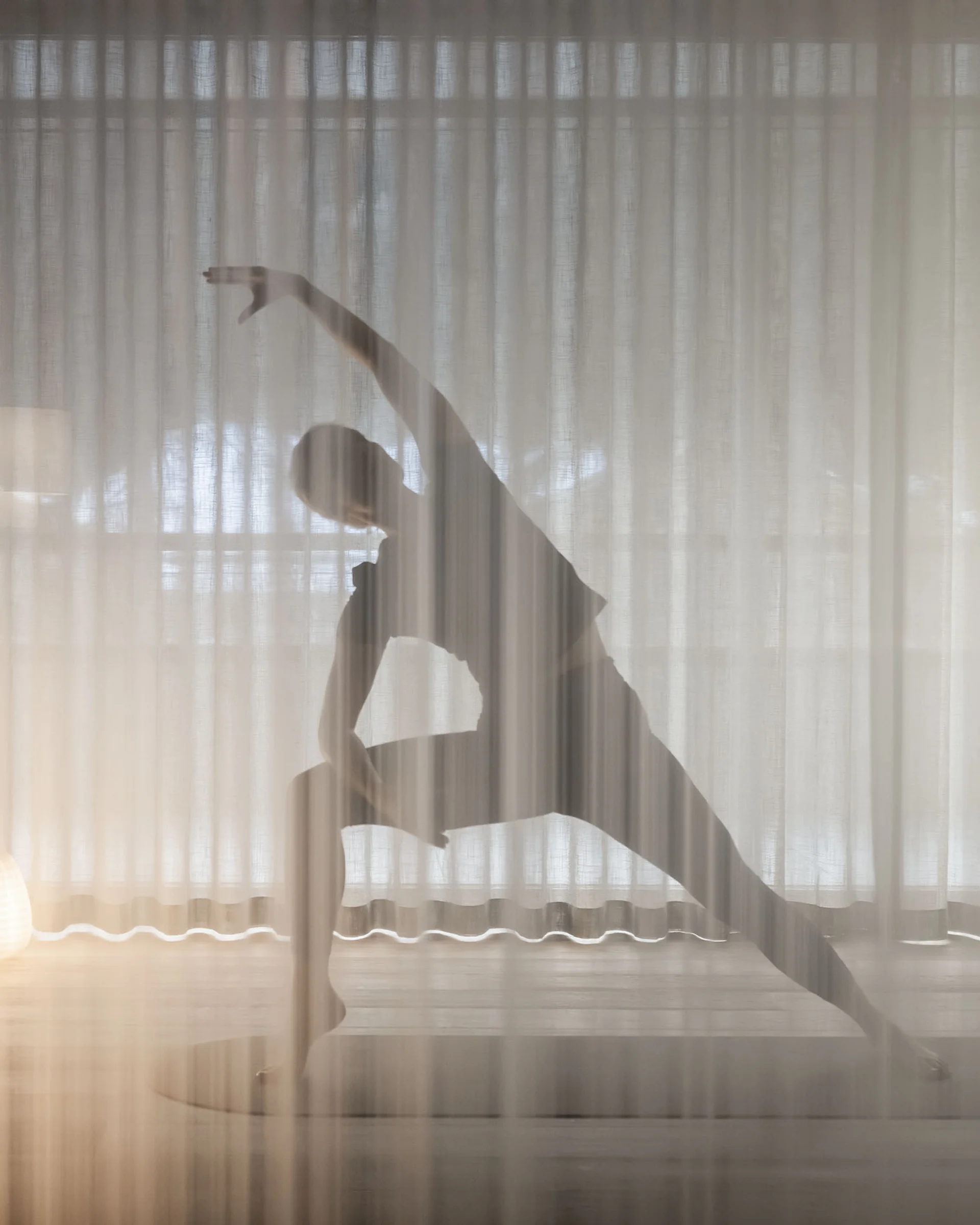 Silhouette beim Yoga-Stretching hinter einem durchsichtigen Vorhang
