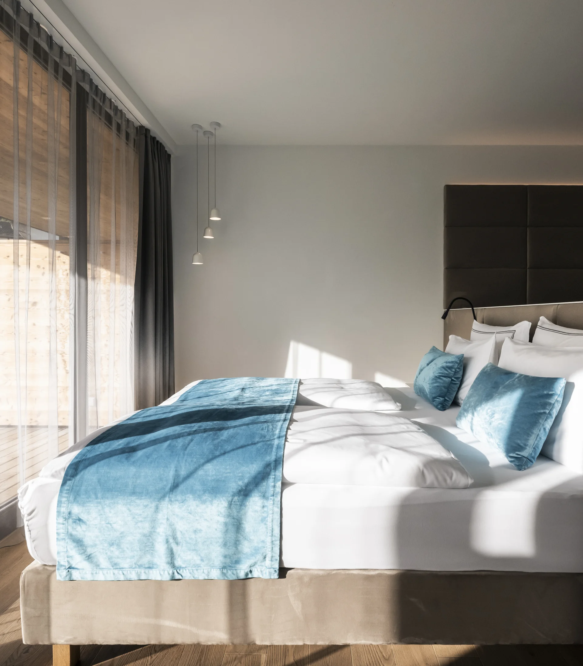 Modern bedroom with large window and blue bed runner