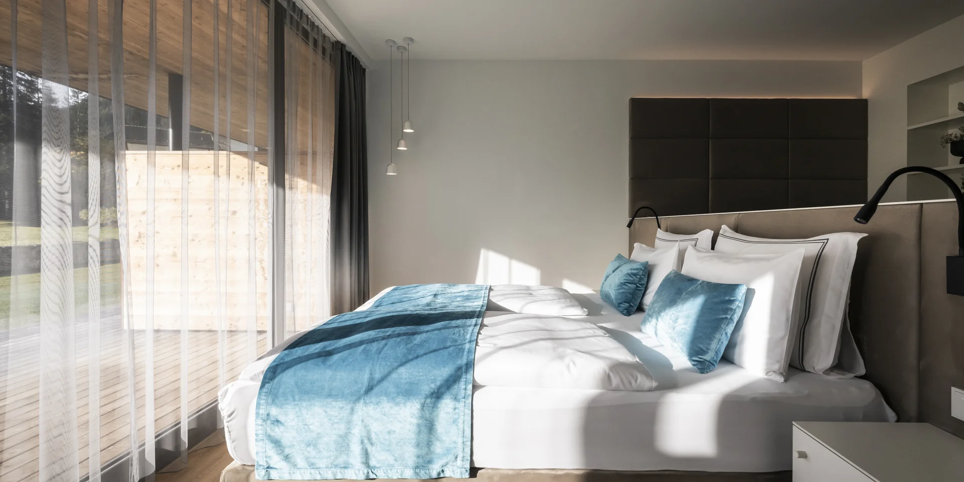 Modernes Schlafzimmer mit großem Fenster und blauem Bettläufer