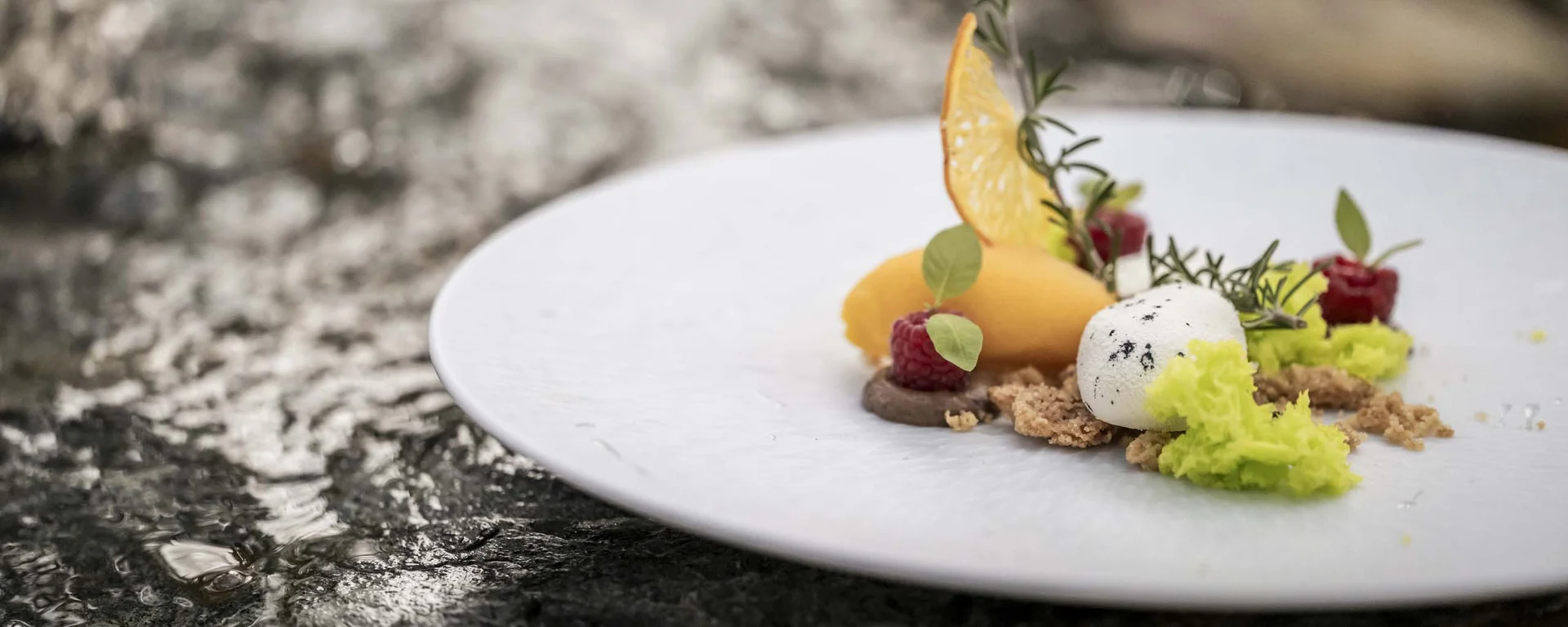 Café the bosco®: ein Ort des Genusses und der Begegnung Kunstvoll angerichtetes Dessert mit Früchten und Kräutern auf weißem Teller
