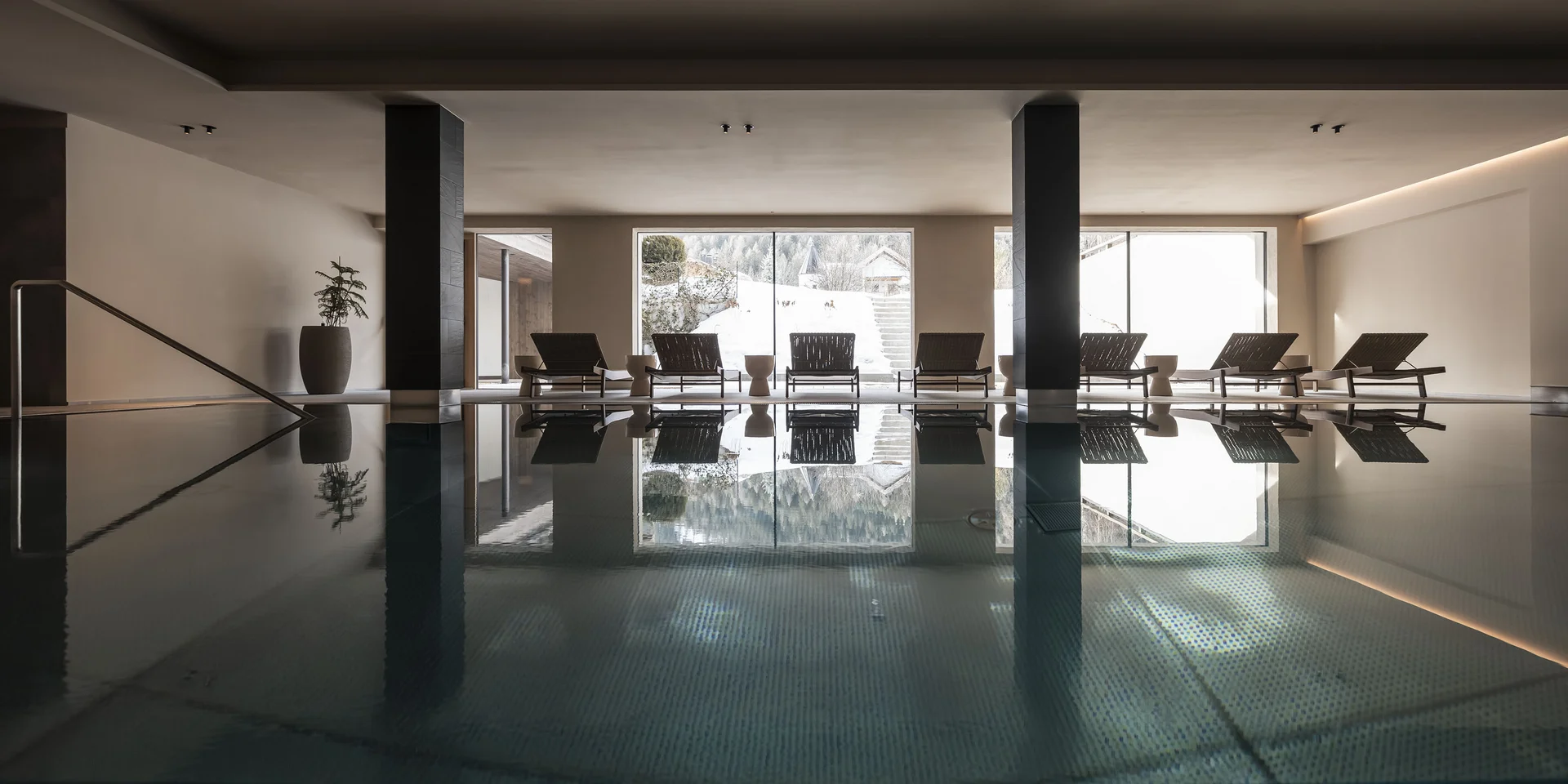 Vista interna di una piscina con lettini davanti a grandi finestre