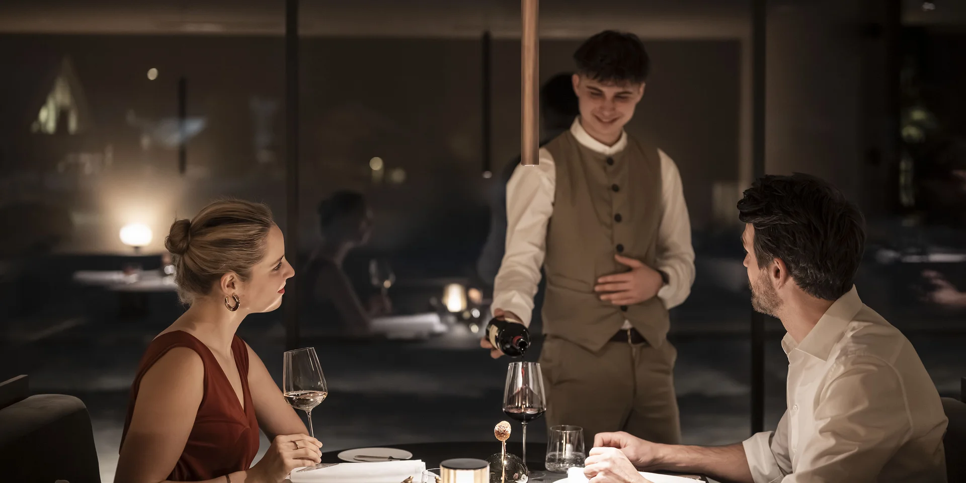 Cameriere versa vino a cena romantica in un ristorante elegante