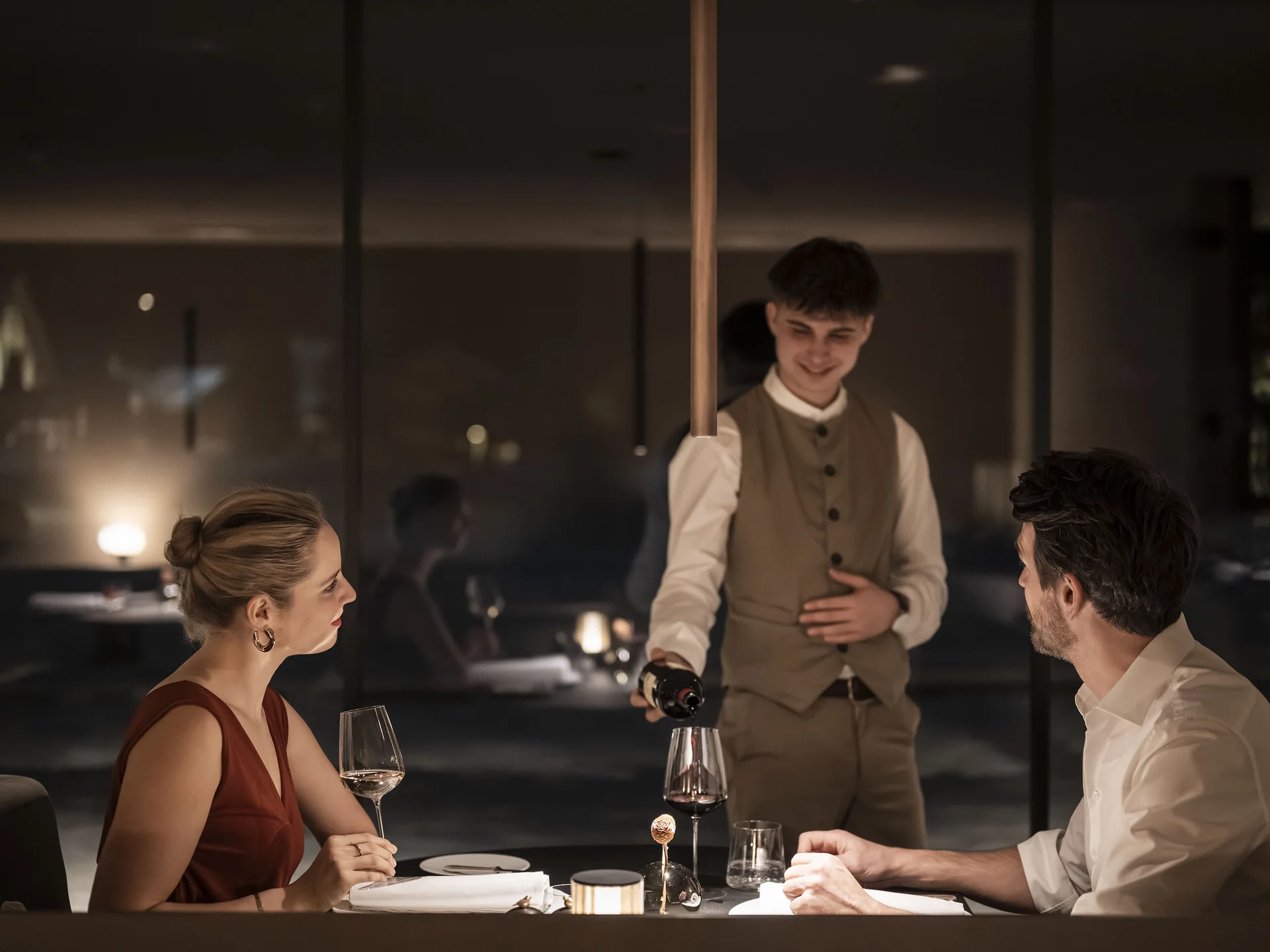 Cameriere versa vino a cena romantica in un ristorante elegante