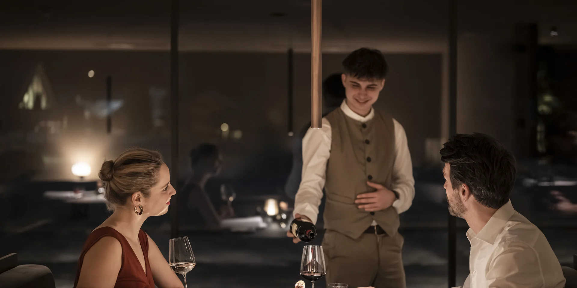 Cameriere versa vino a cena romantica in un ristorante elegante