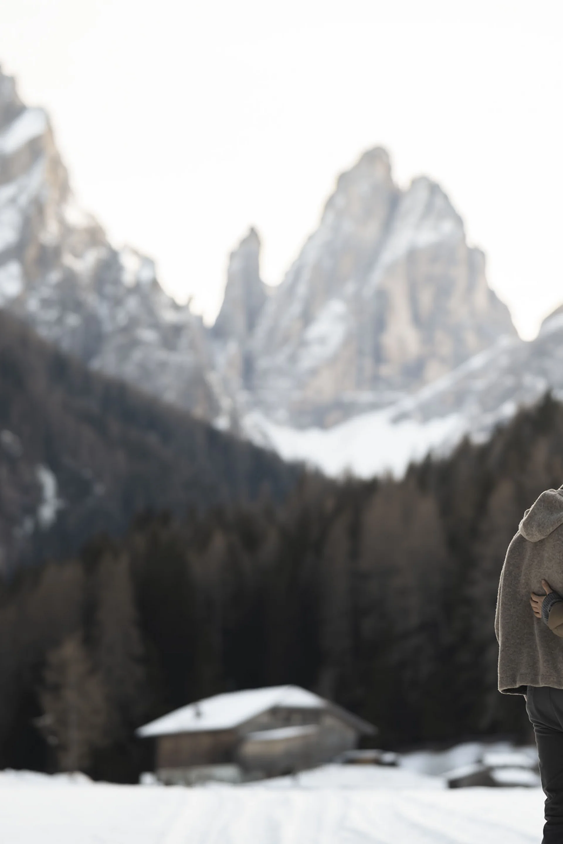 Couple hugging in snowy mountain landscape with wooden cabins