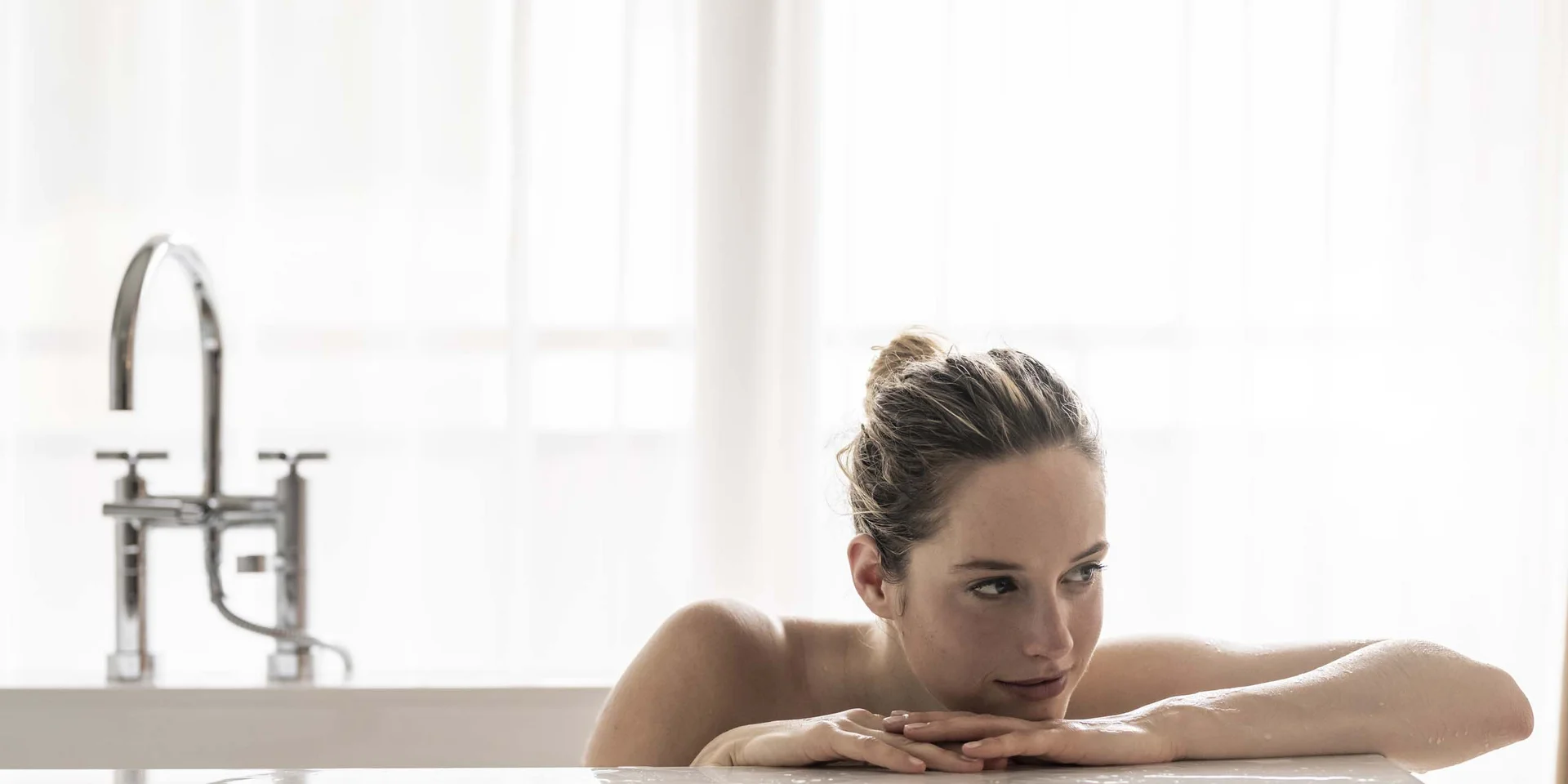 Frau entspannt in der Badewanne vor hellem Fenster