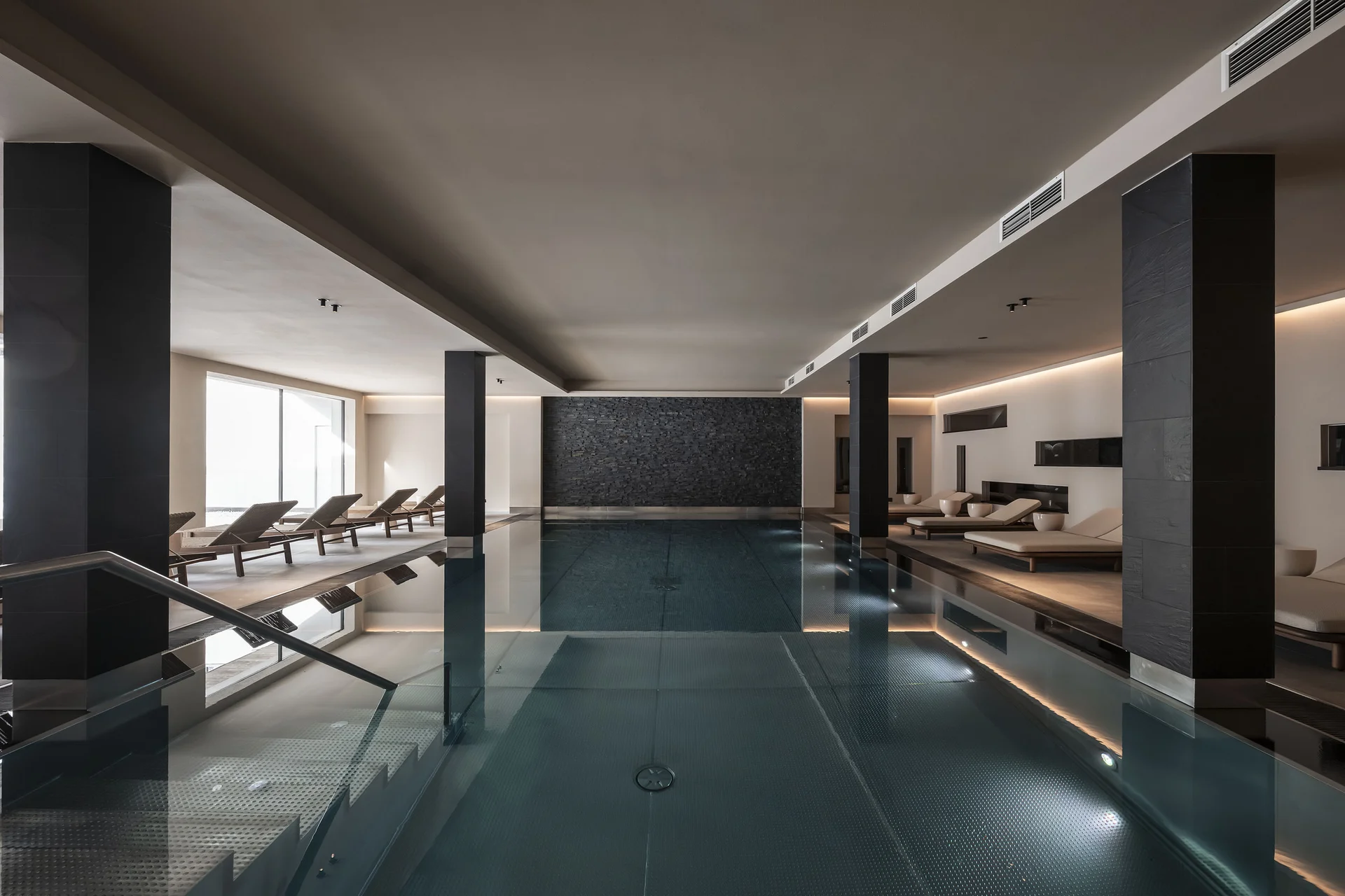 Moderner, stilvoller Innenpool mit Liegestühlen und gedämpfter Beleuchtung