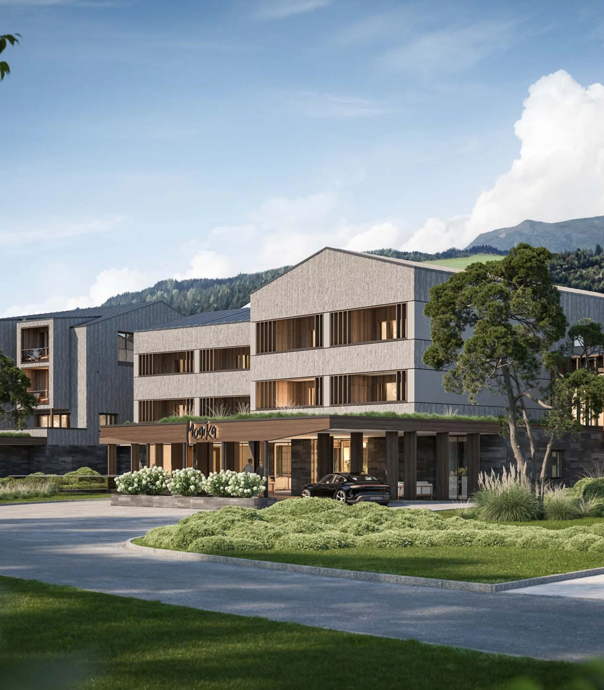 Modern hotel building surrounded by greenery with mountains in the background