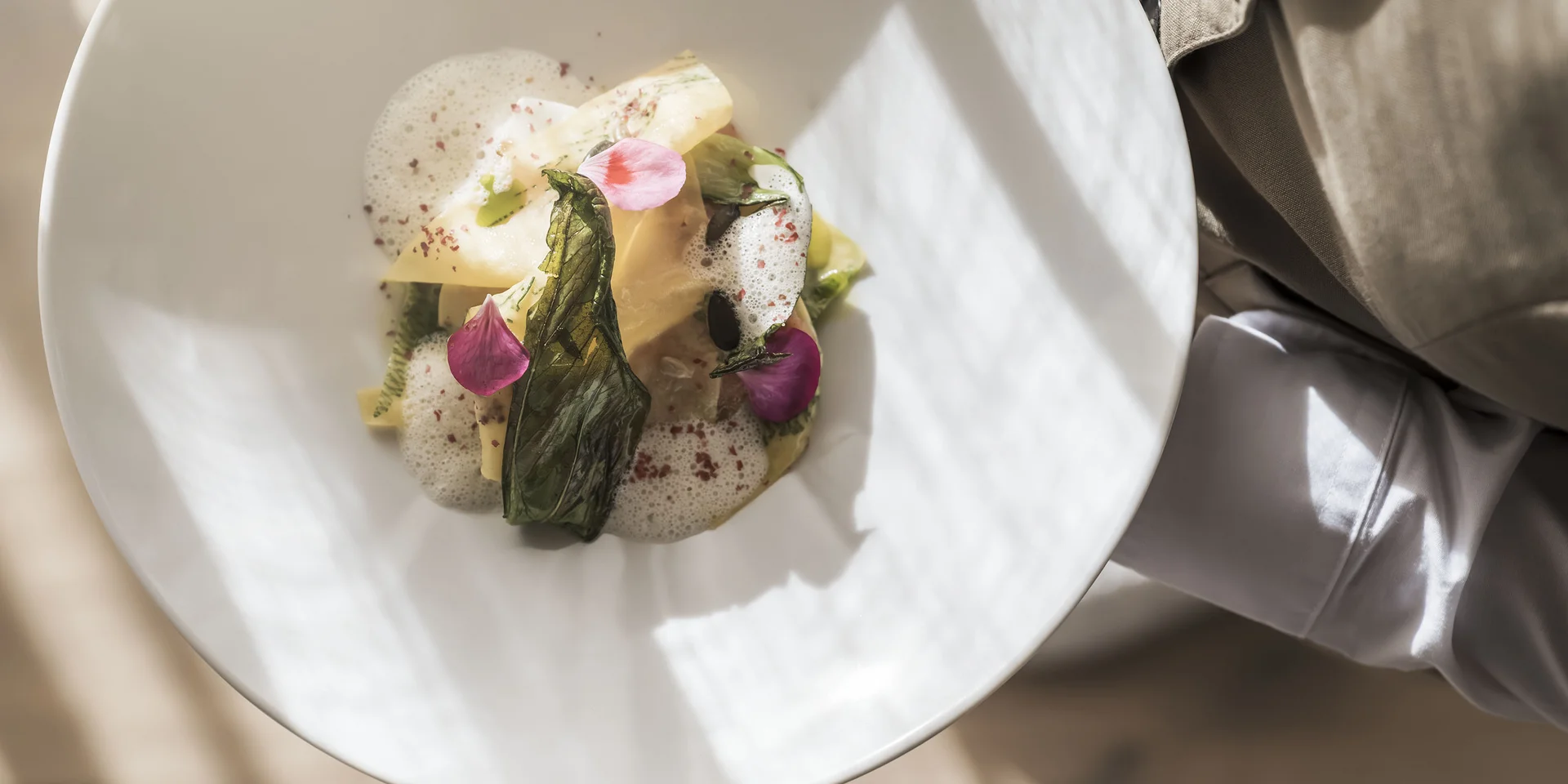 Piatti gourmet con decorazioni di foglie e petali su piatto bianco