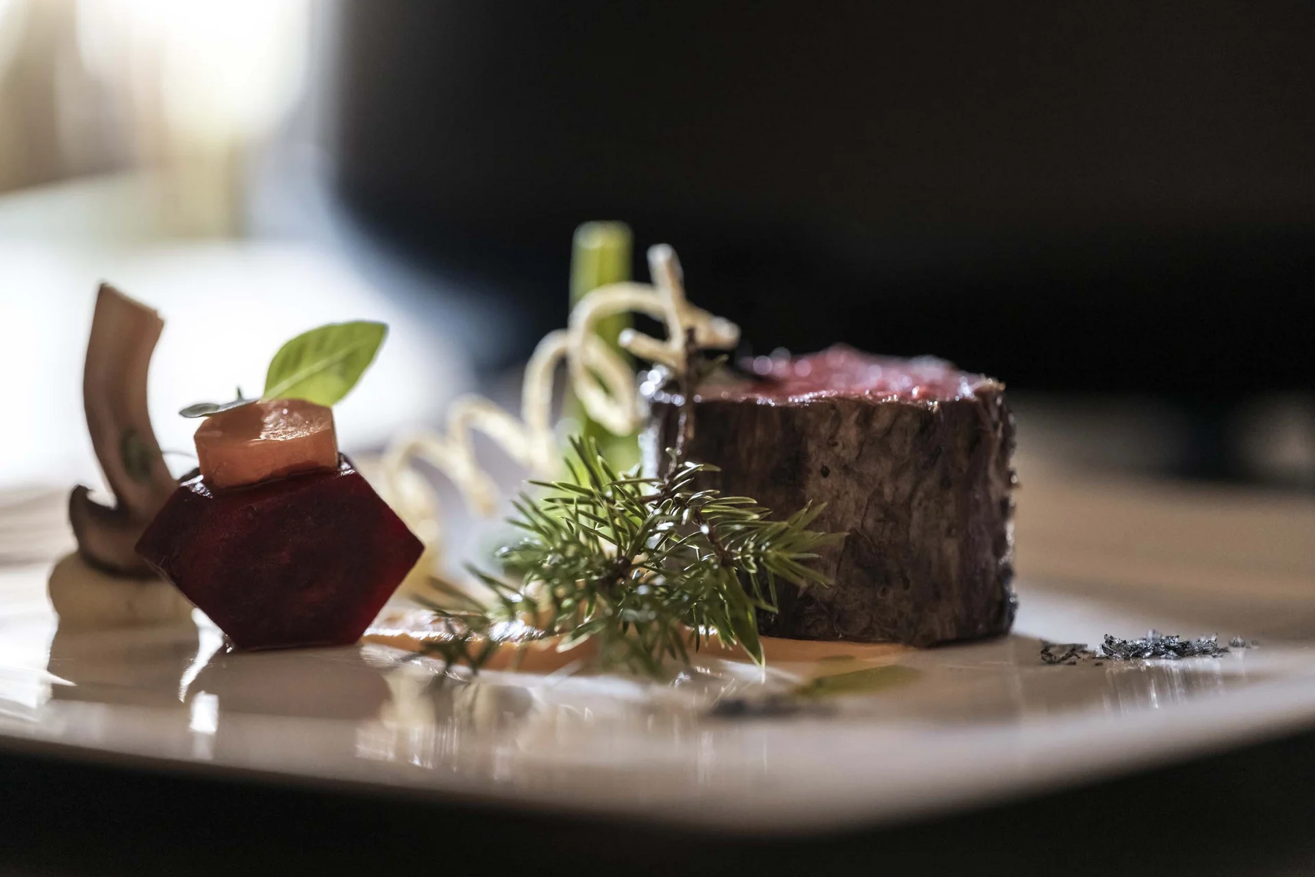 À-la-carte-Restaurant CANA in Sexten Gourmetgericht mit Rindfleisch, Gemüse und Kräutern elegant angerichtet
