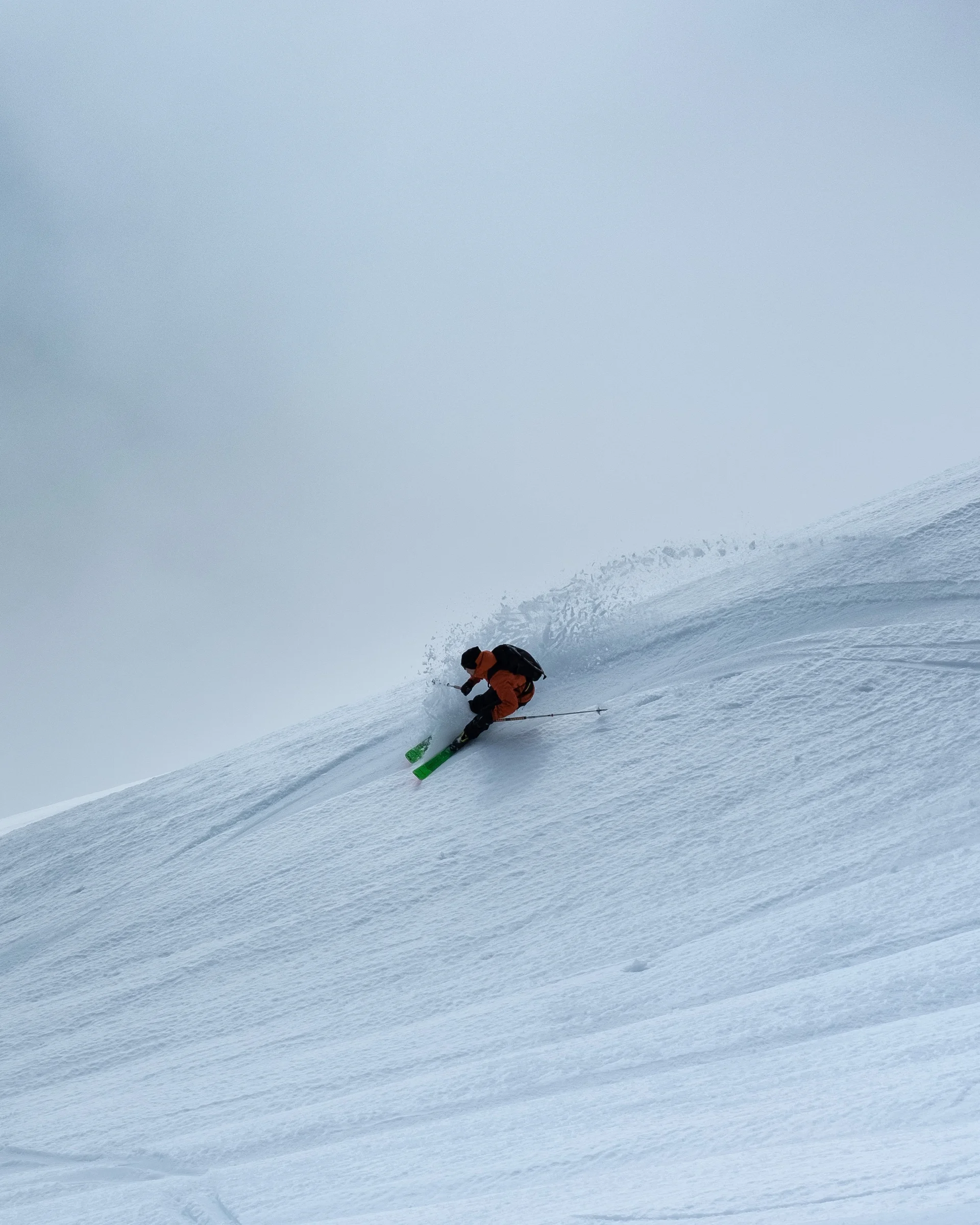 Skifahrer fährt steilen, verschneiten Berg im Nebel hinunter