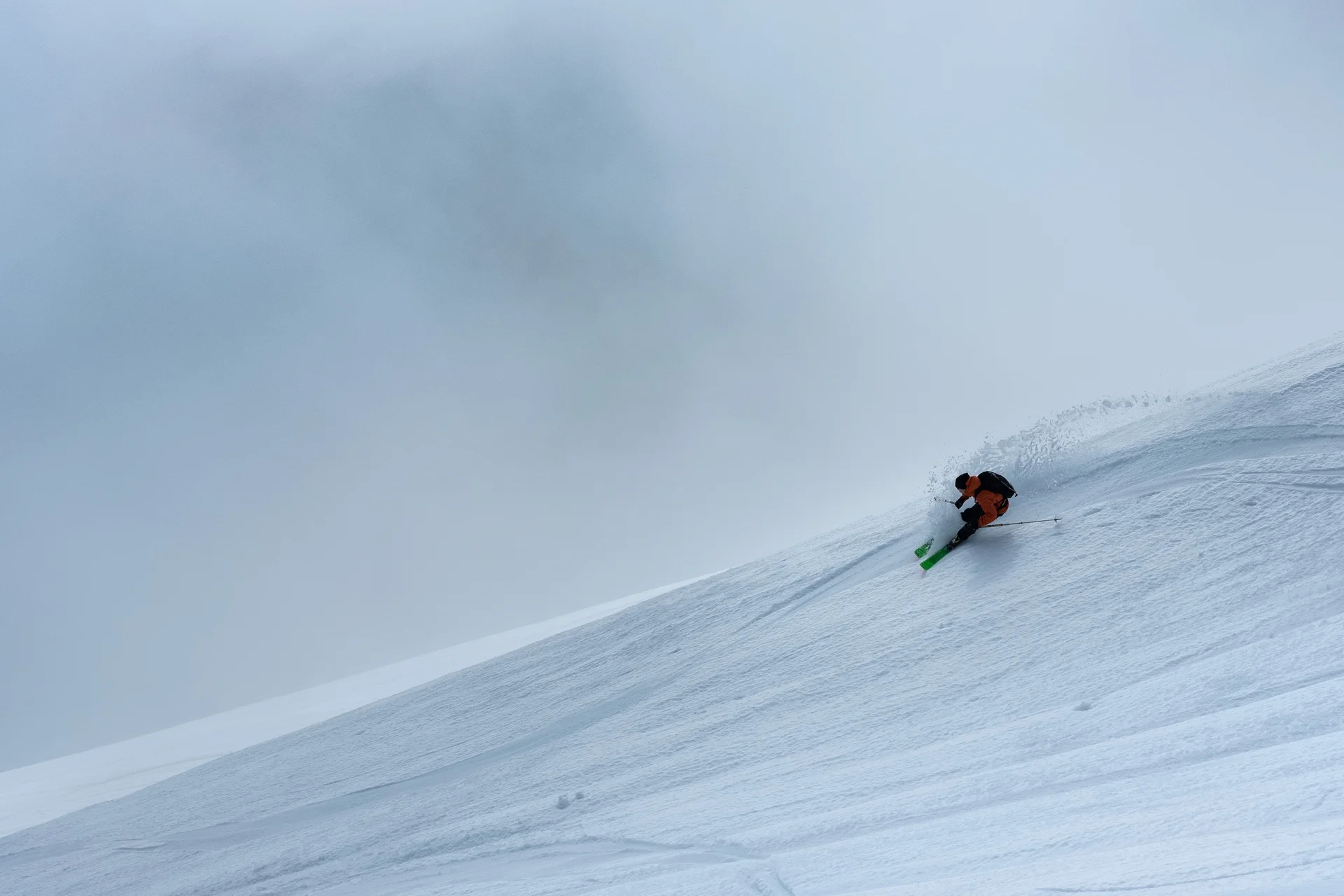 Skifahrer fährt steilen, verschneiten Berg im Nebel hinunter