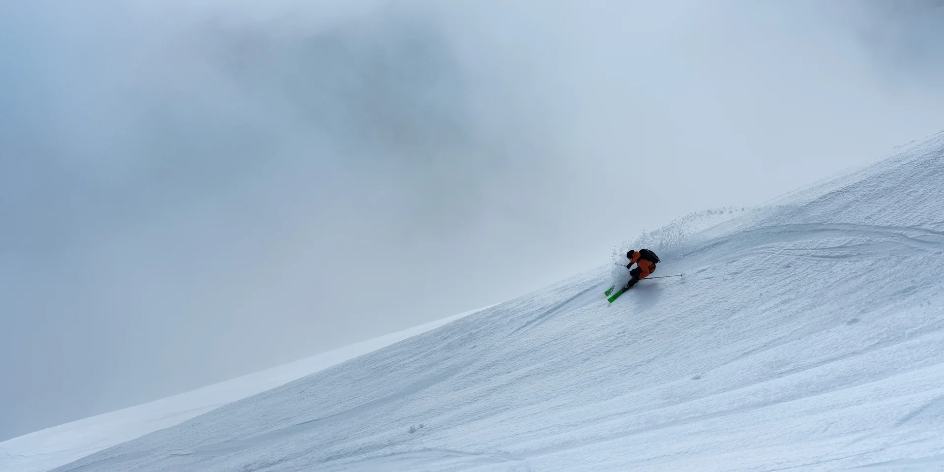 Skifahrer fährt steilen, verschneiten Berg im Nebel hinunter
