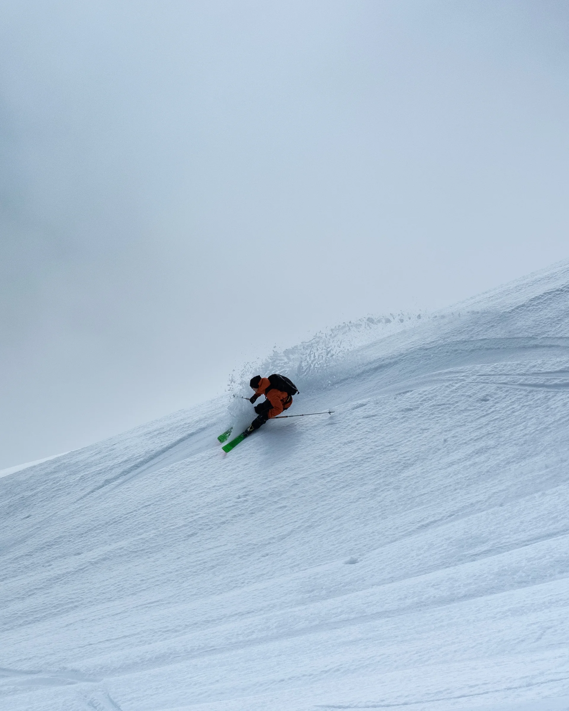Skifahrer fährt steilen, verschneiten Berg im Nebel hinunter