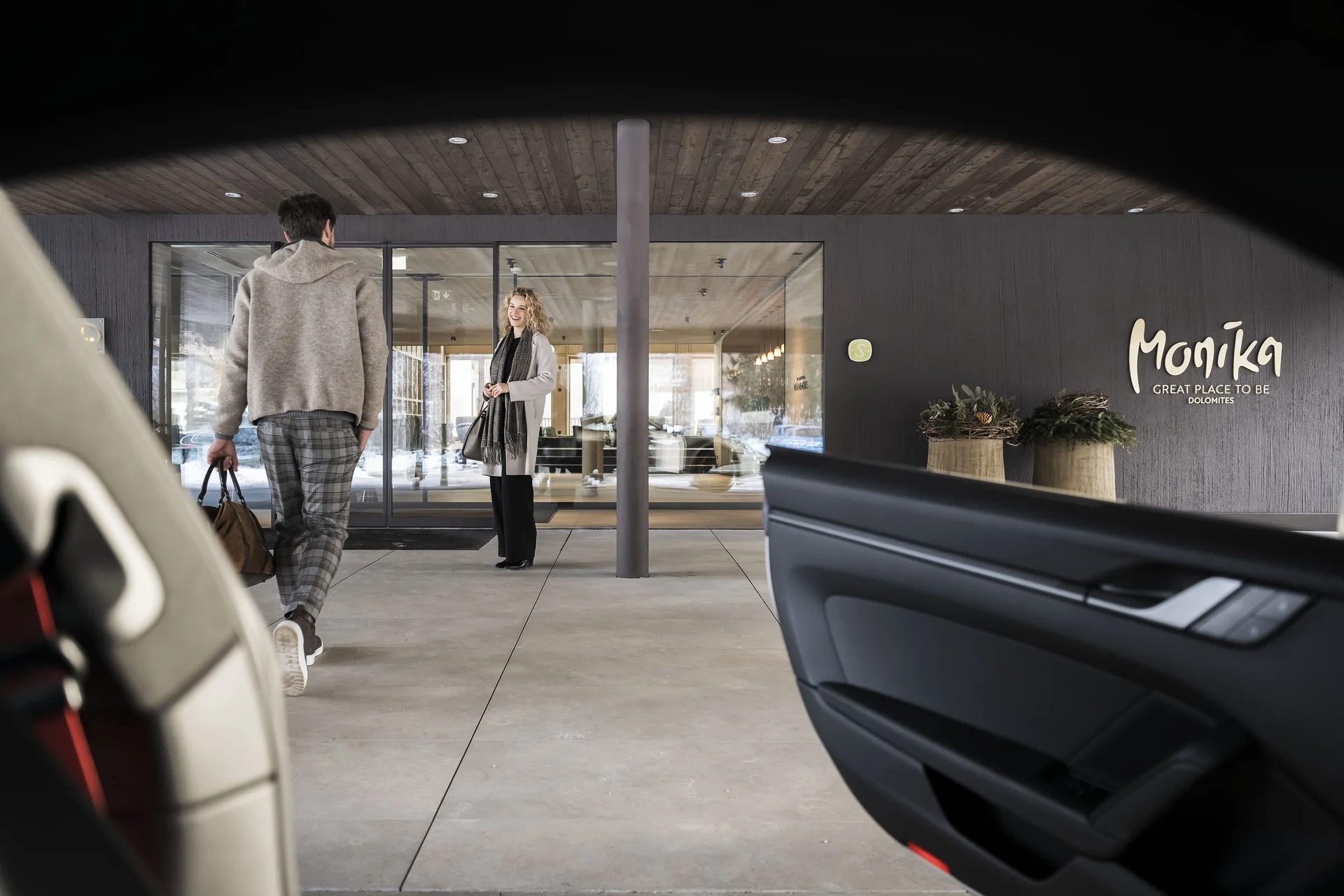 Person geht zum Eingang eines modernen Gebäudes mit Monika Schriftzug