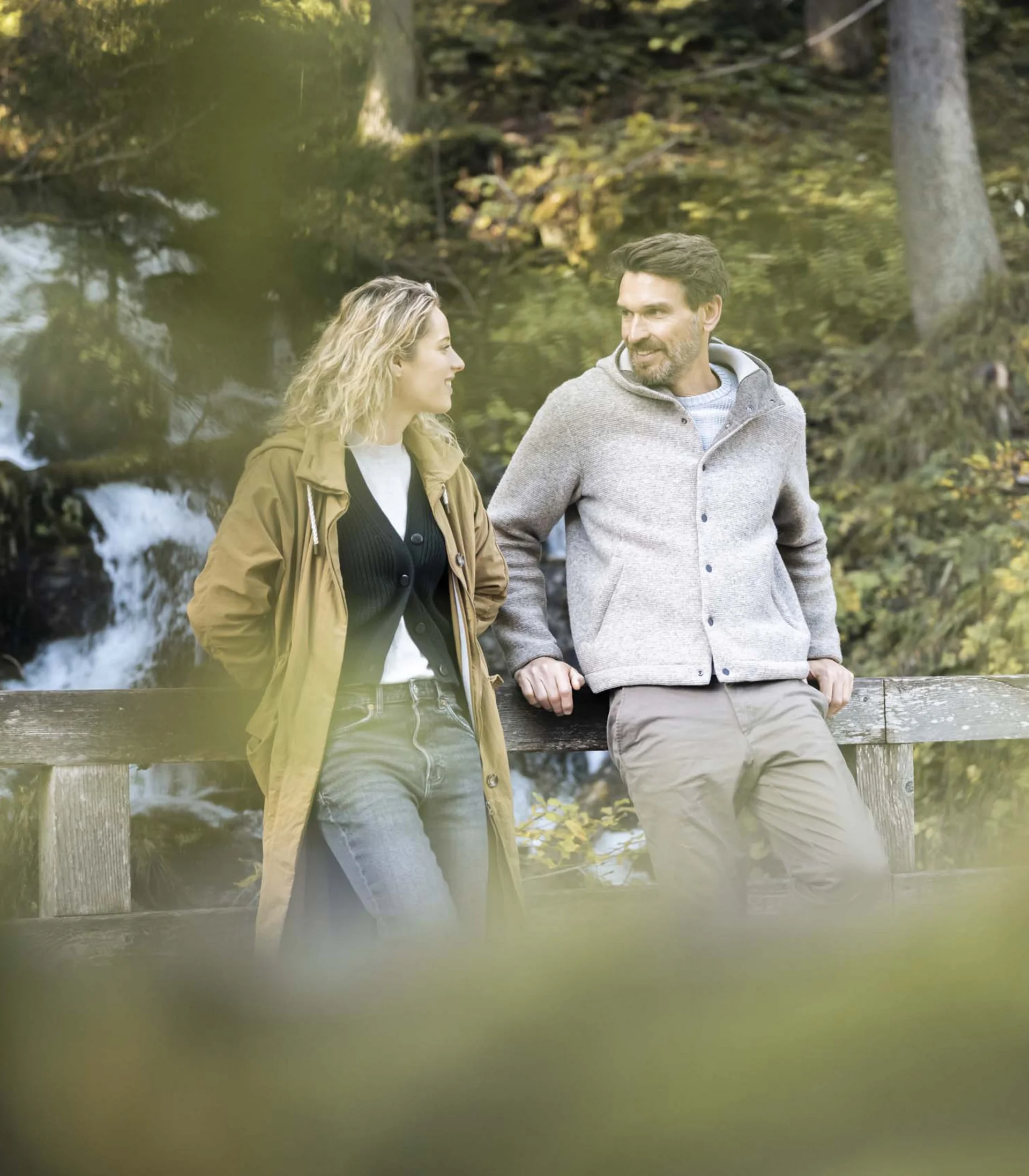 Paar steht auf Brücke vor Wasserfall im Wald