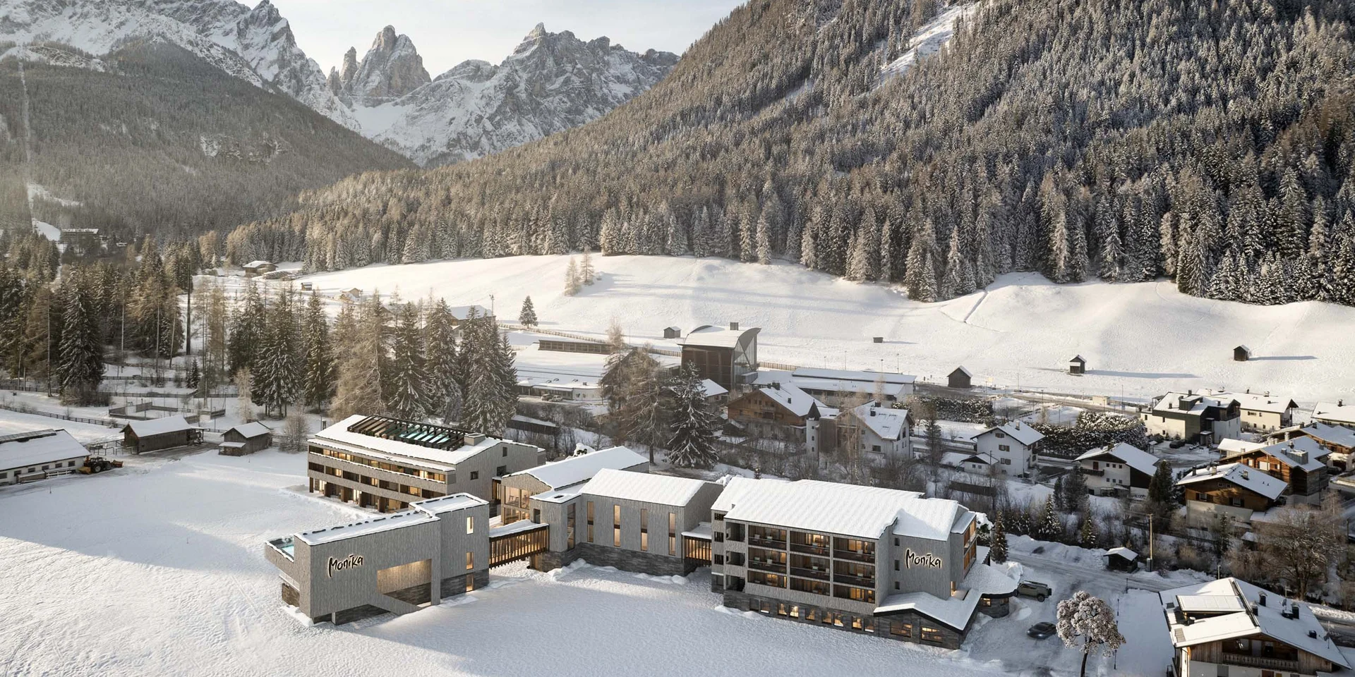 Hotel Monika in snowy valley with mountains and forest in the background