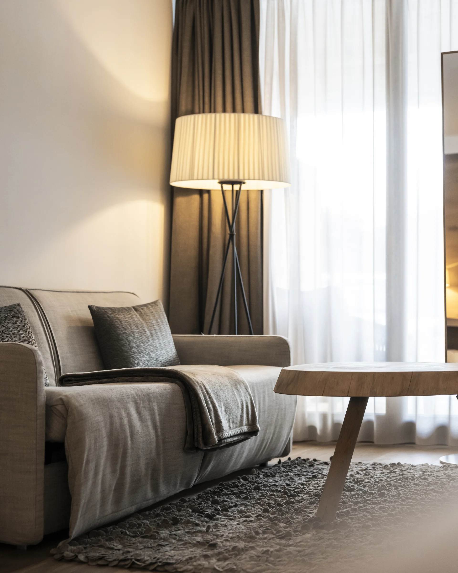 Modernes Wohnzimmer mit Sofa, Stehlampe und rundem Holztisch