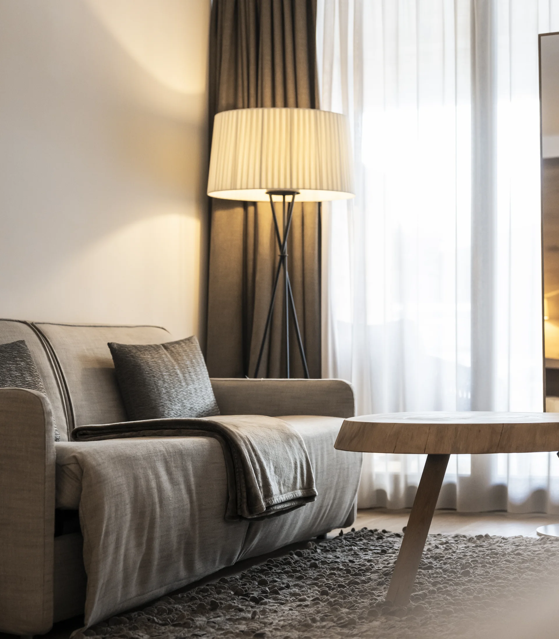 Modernes Wohnzimmer mit Sofa, Stehlampe und rundem Holztisch