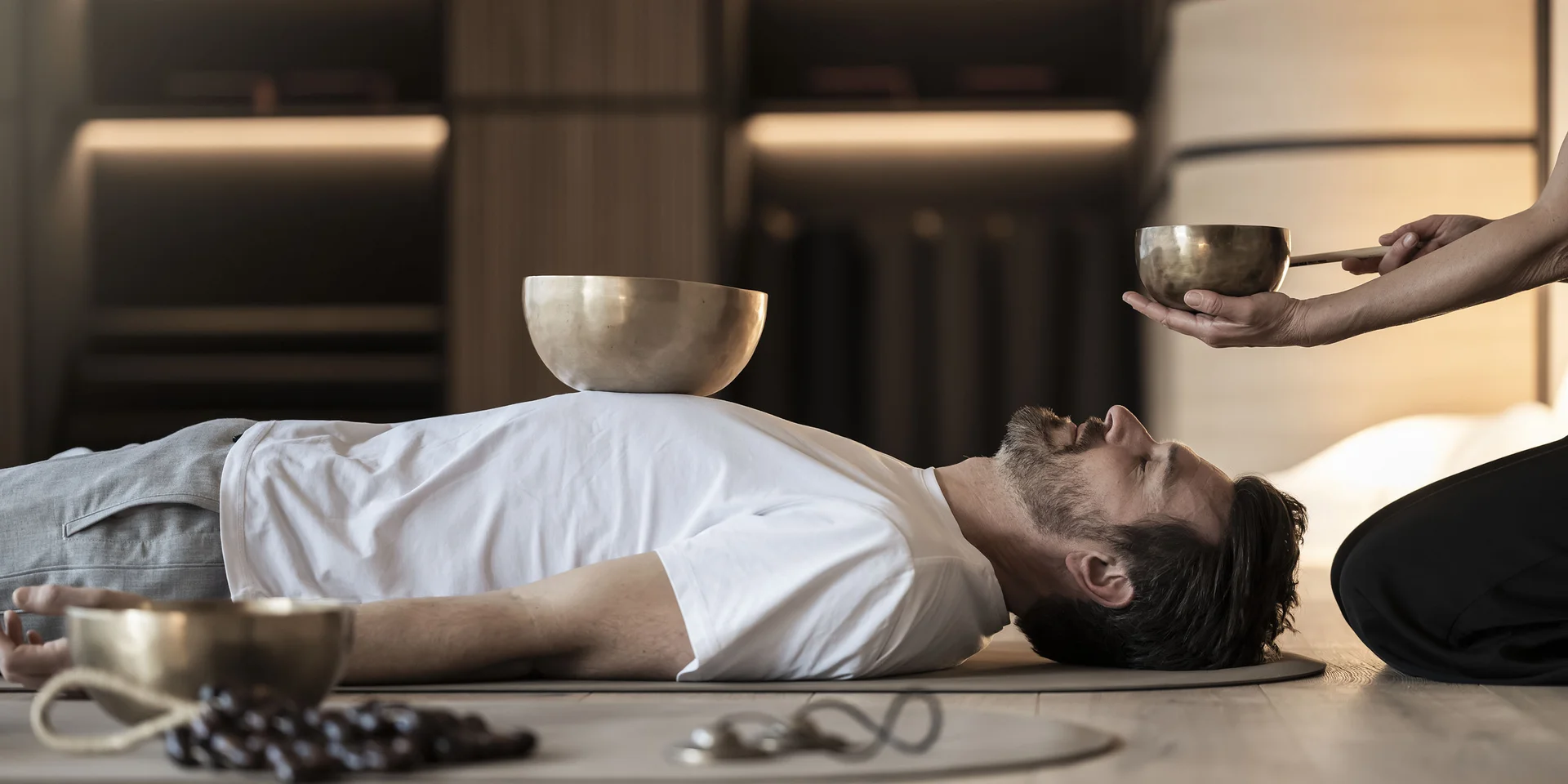 Uomo sdraiato per terapia del suono con campane tibetane