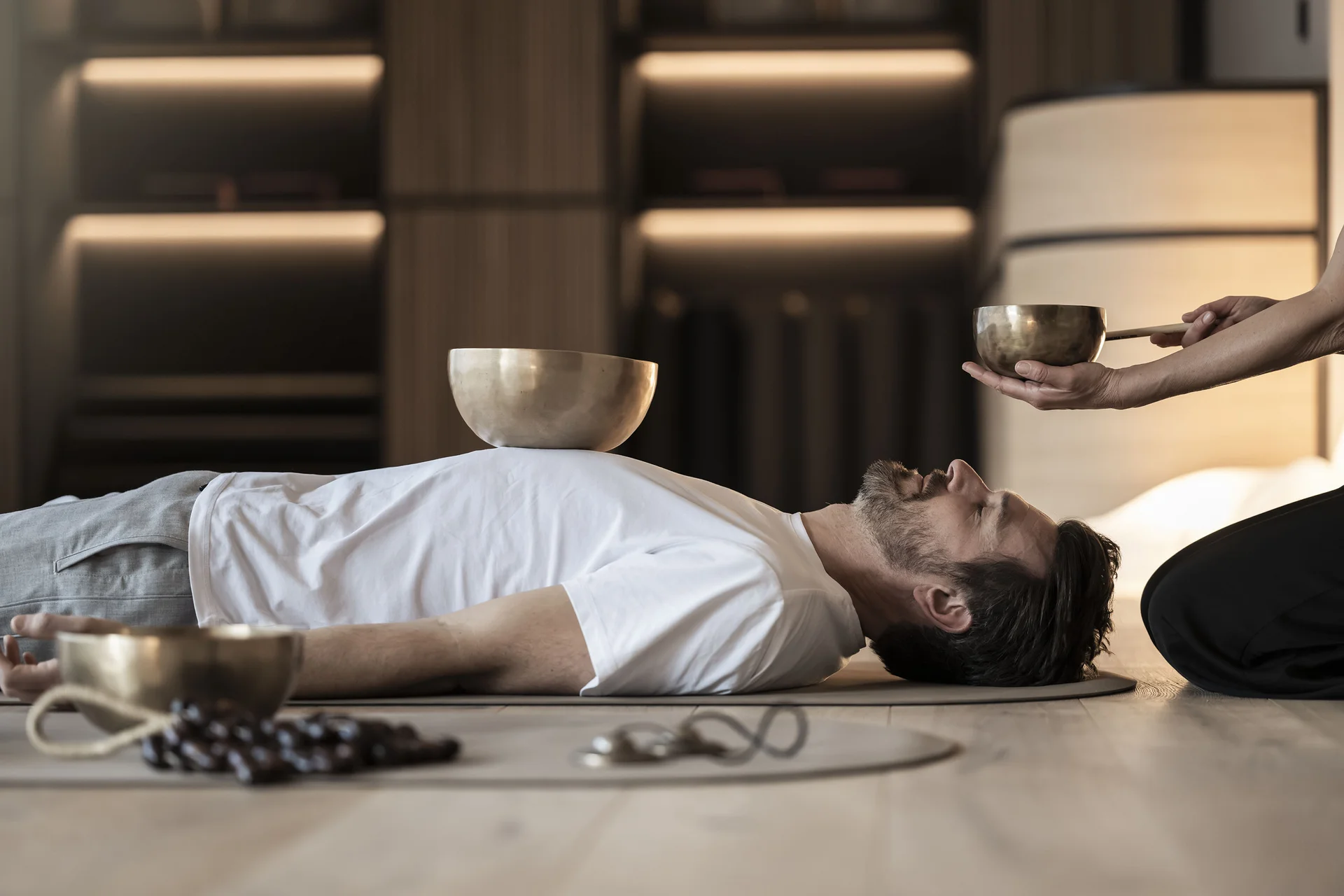 Uomo sdraiato per terapia del suono con campane tibetane