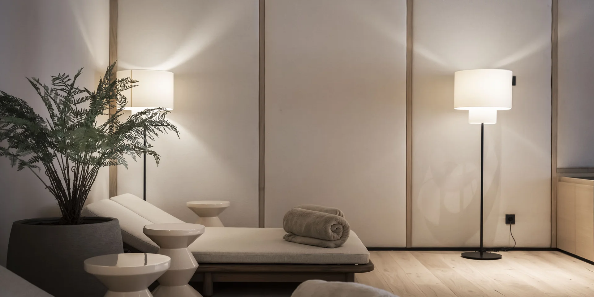 Sala relax moderna con lettini, asciugamani arrotolati e lampade da terra