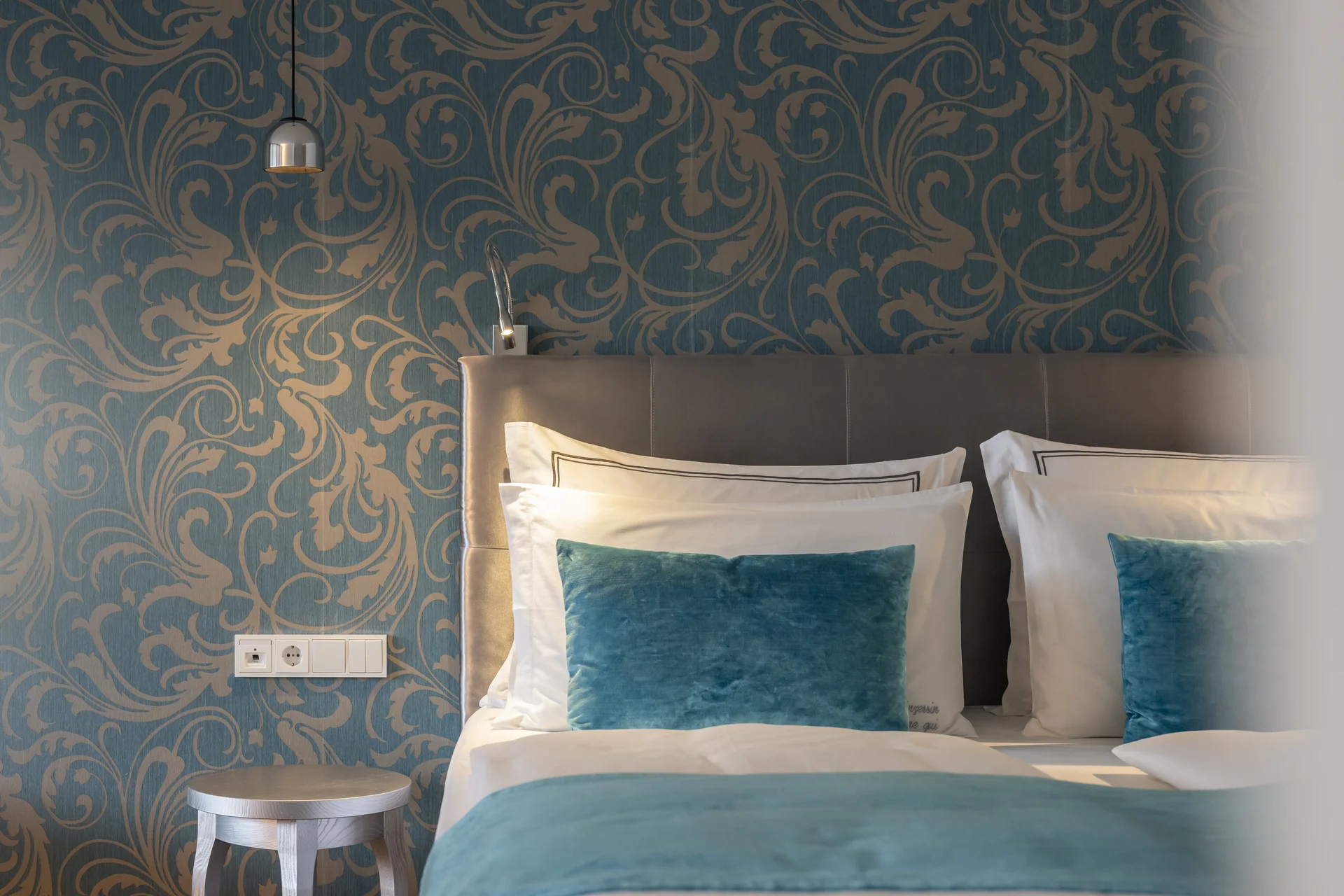 Nahaufnahme von Betten mit blauen Kissen und gemusterten Tapeten im Zimmer