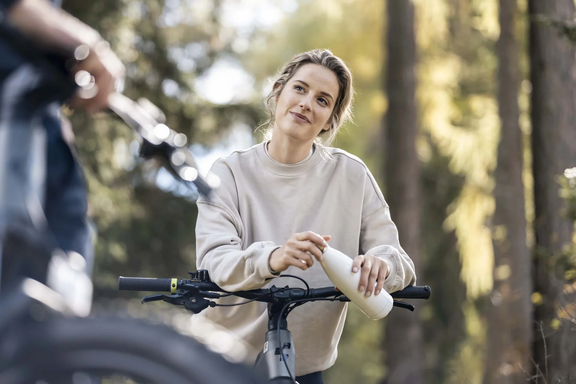 Fitness, Yoga, Outdoor-Erlebnisse: Aktivhotel in Südtirol Frau mit Fahrrad trinkt aus Flasche im Wald bei Tageslicht