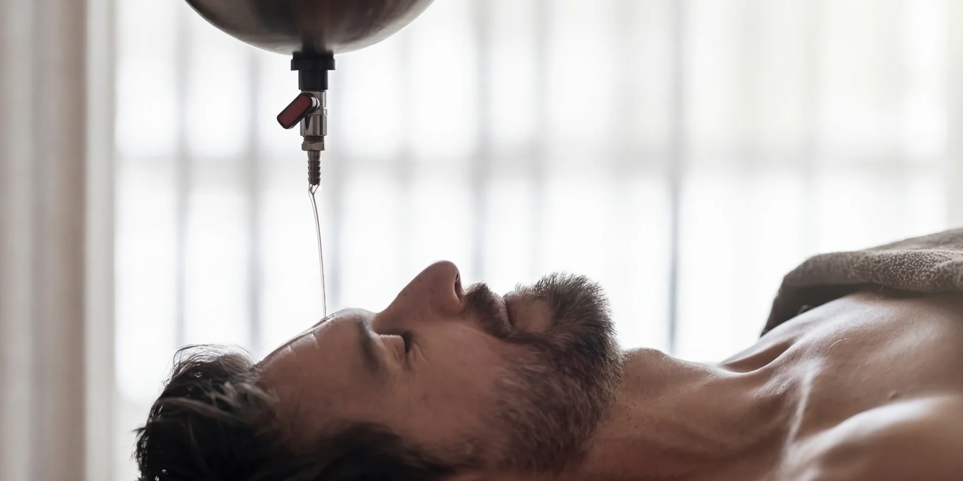 Uomo sdraiato riceve gocce sulla fronte in un centro benessere