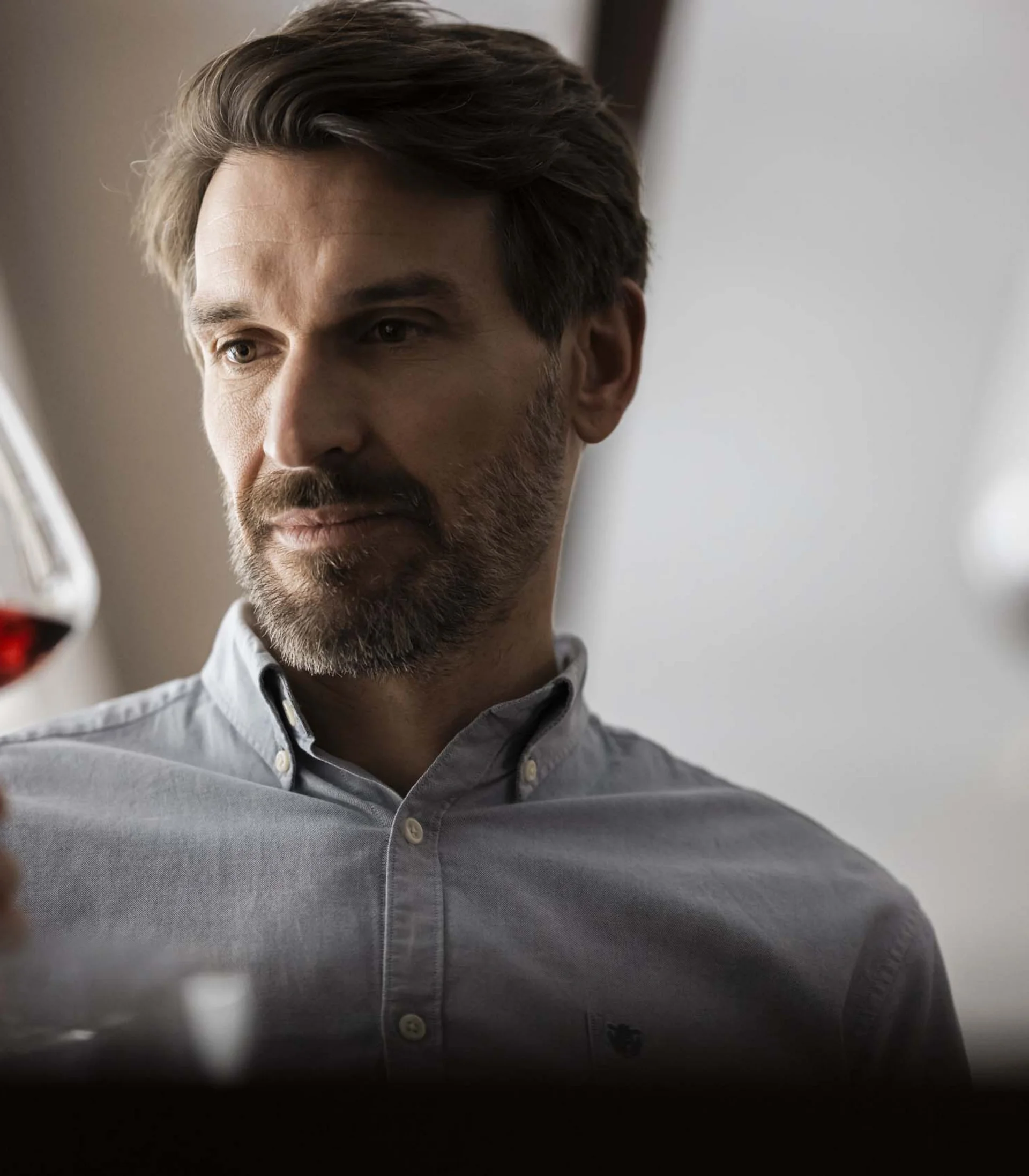 Mann betrachtet ein Glas Rotwein genau