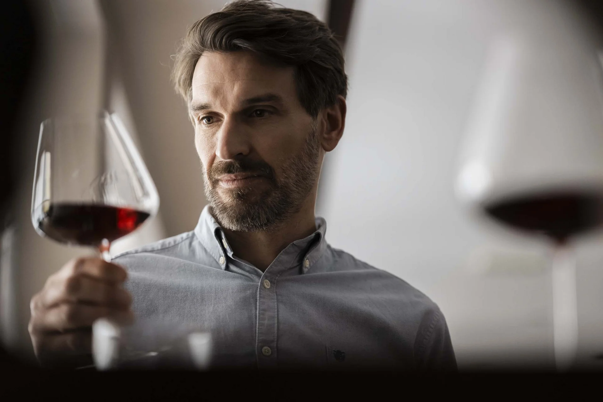 Mann betrachtet ein Glas Rotwein genau