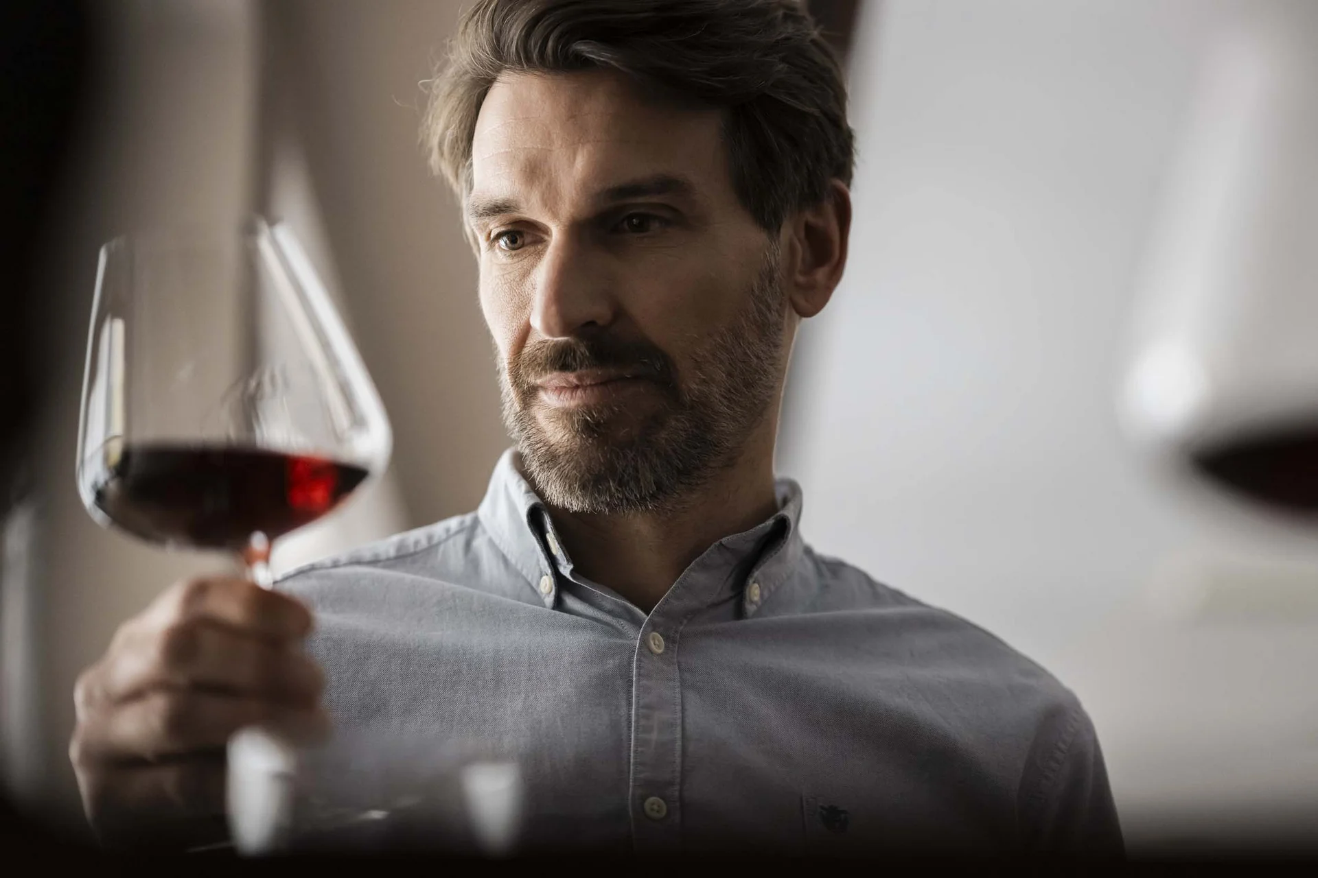 Natürlicher Genuss: Ihr Hotel mit Halbpension in Südtirol Mann betrachtet ein Glas Rotwein genau