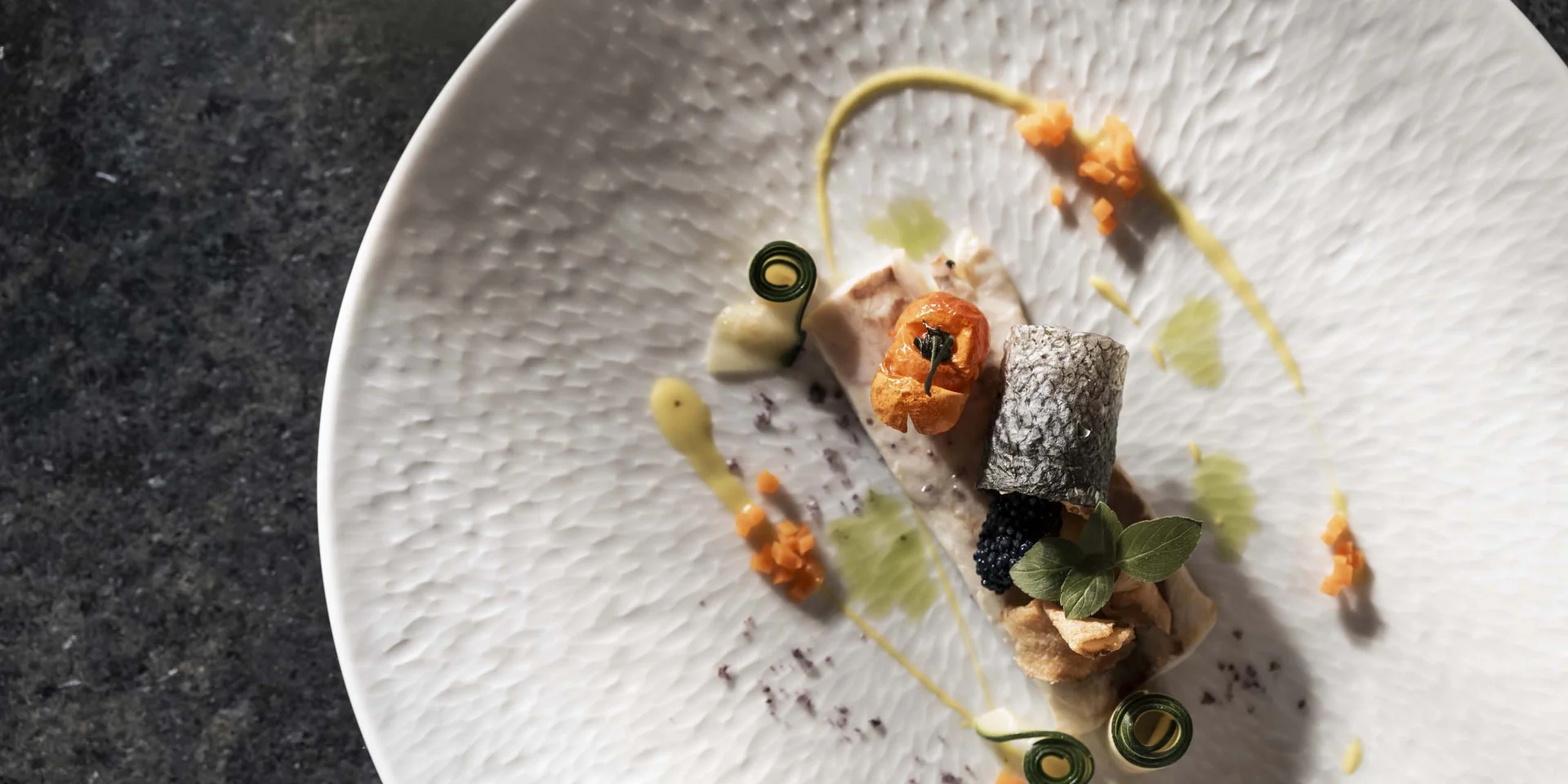 Kunstvoll angerichtetes Gourmet-Fischgericht auf weißem Teller