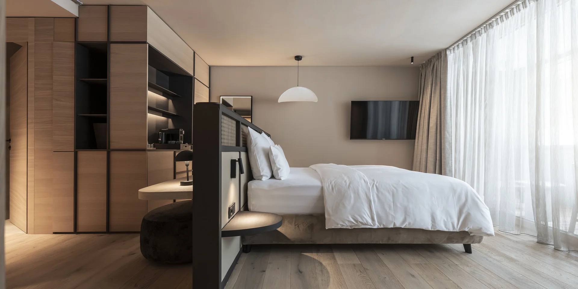 Camera d'hotel moderna con letto grande e finestre a tutta altezza