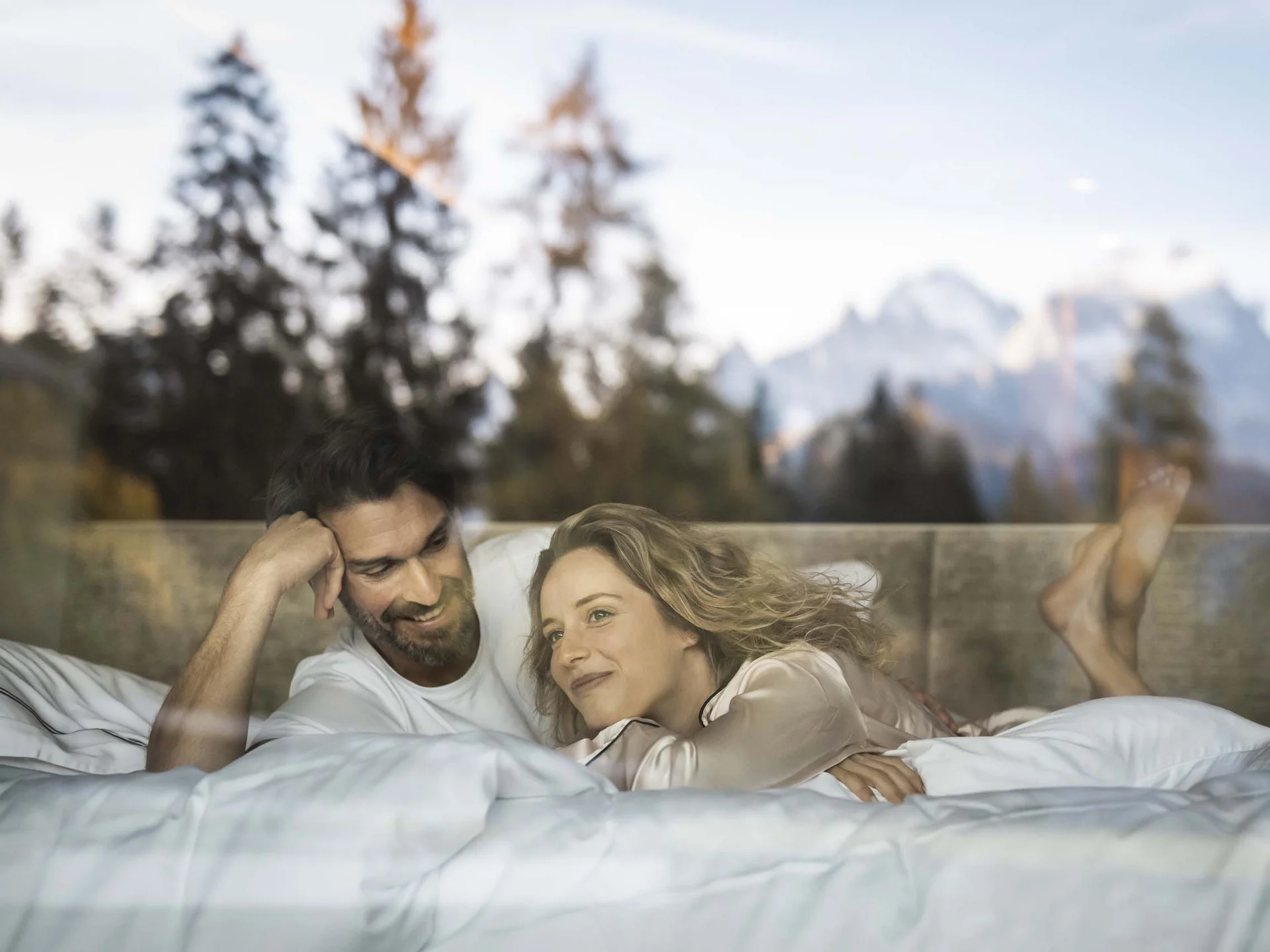 Hotel Monika: das romantische Hotel in Südtirol Paar liegt entspannend im Bett mit Bergblick und Bäumen draußen