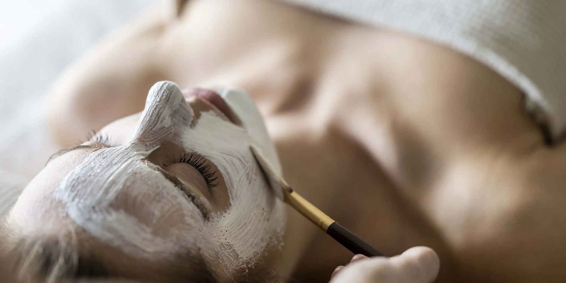 Donna riceve una maschera viso applicata con pennello in una spa