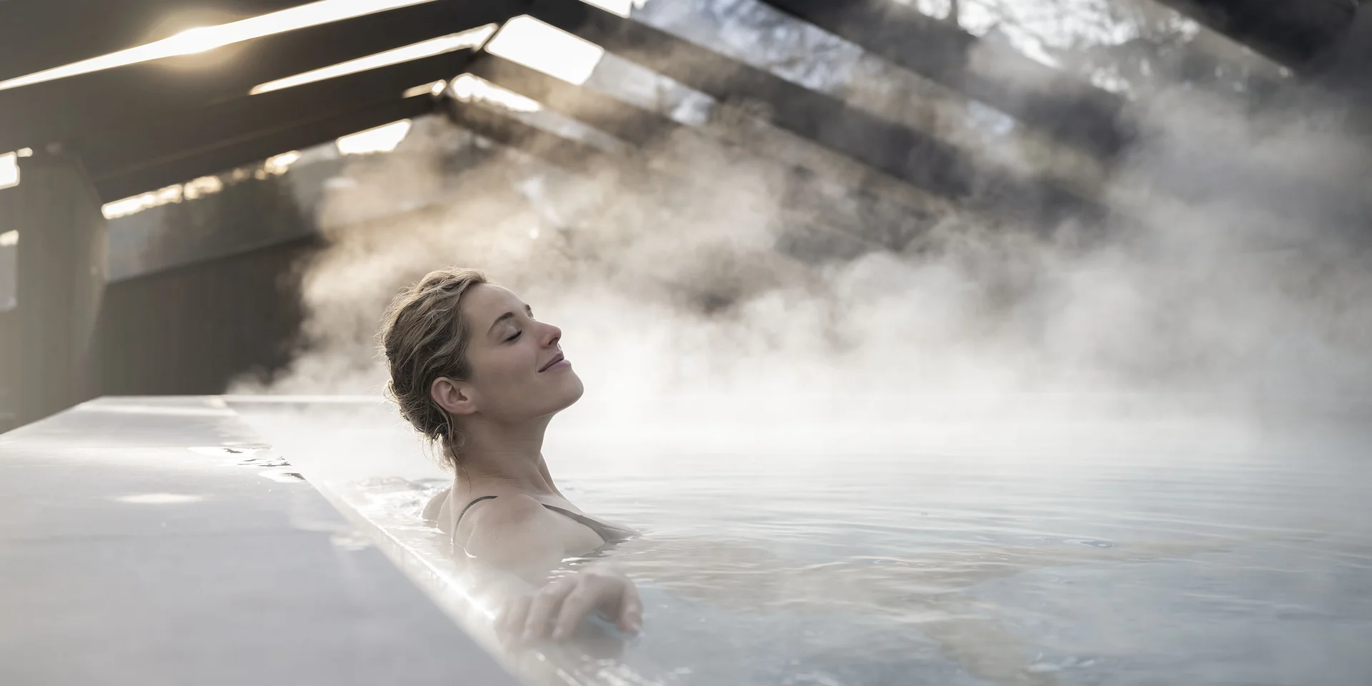 Donna rilassata in piscina termale con vapore sotto una copertura di vetro