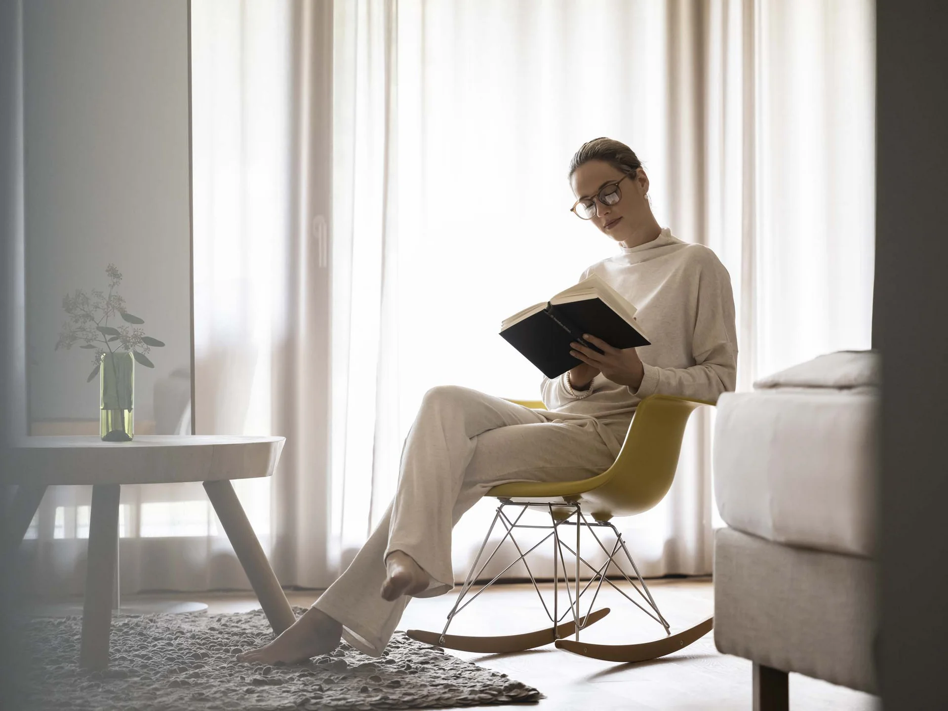 Hotel Monika: Ihr Adults-only-Wellnesshotel in Südtirol Frau liest Buch entspannt auf einem gelben Schaukelstuhl im Wohnzimmer