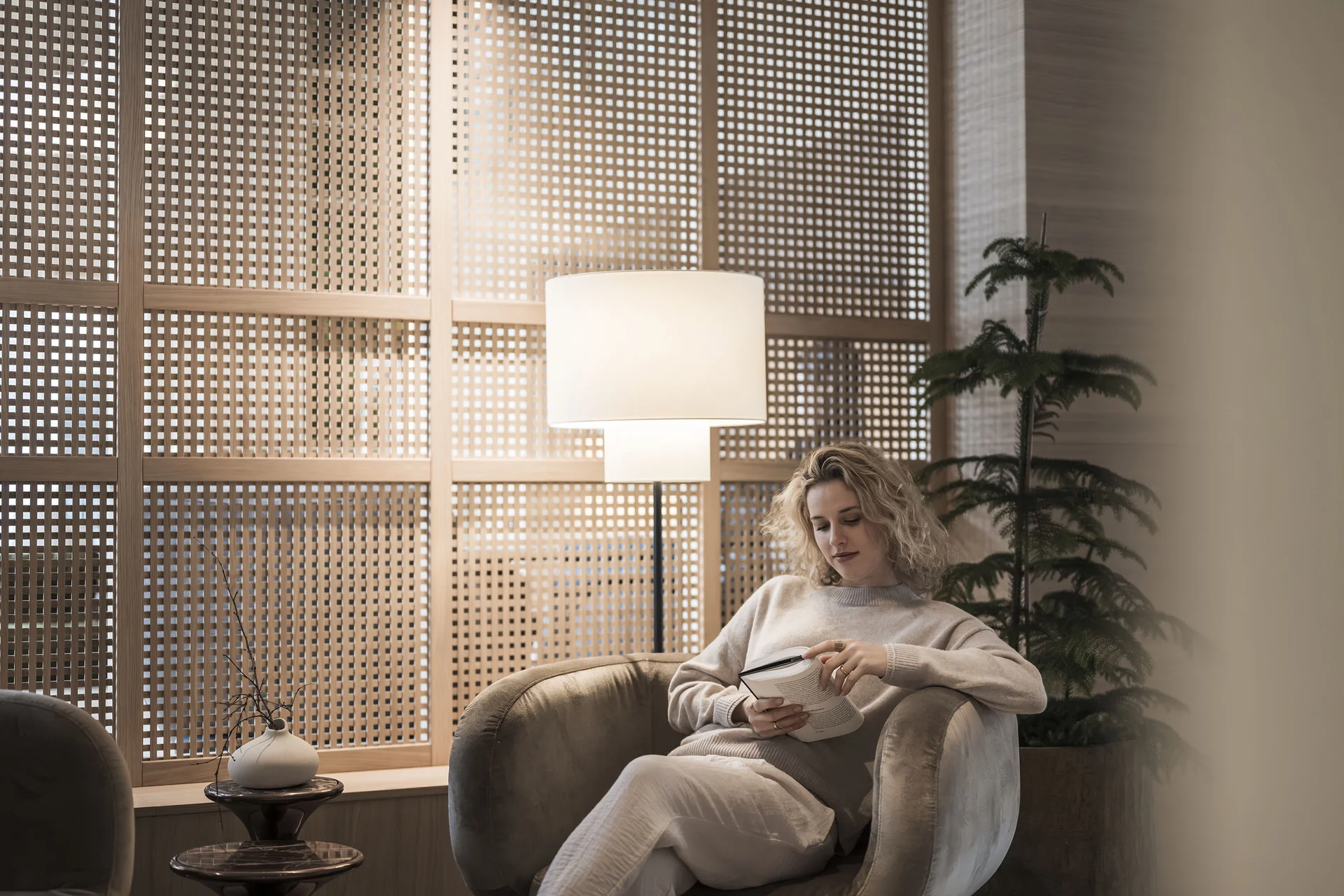 Frau liest entspannt Buch in gemütlichem Stuhl bei warmem Licht