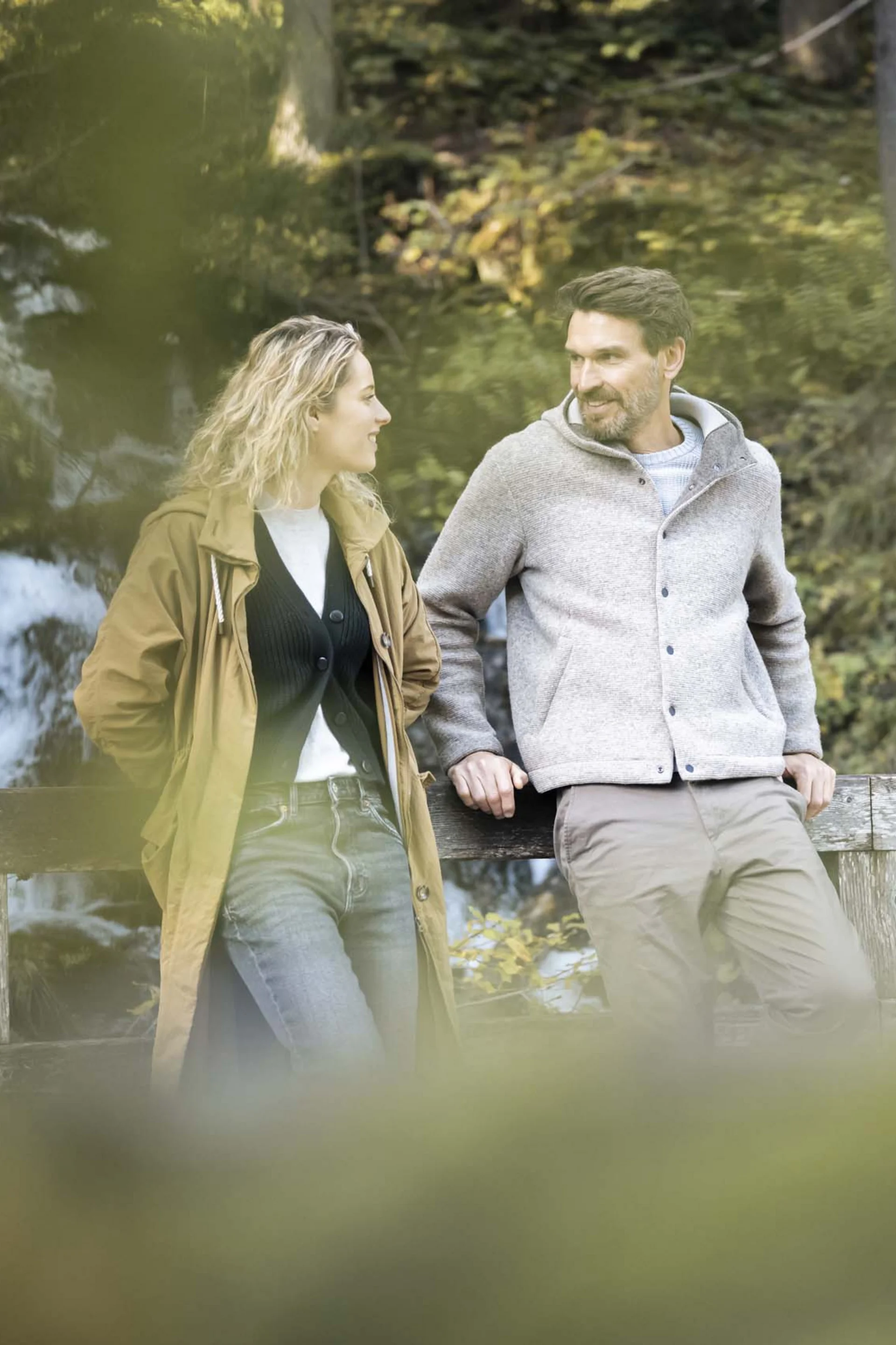 Couple standing on bridge by waterfall in forest