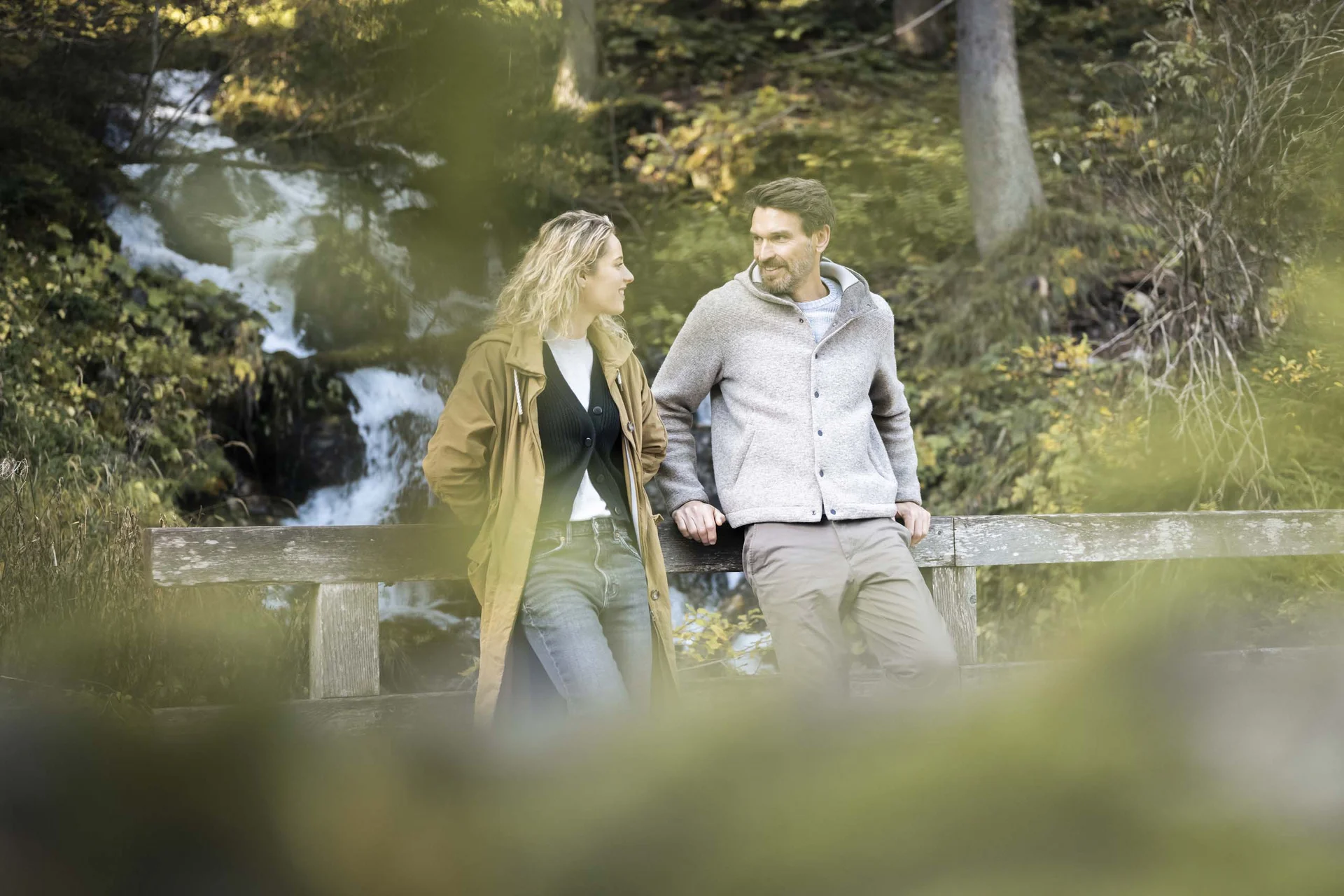 Couple standing on bridge by waterfall in forest