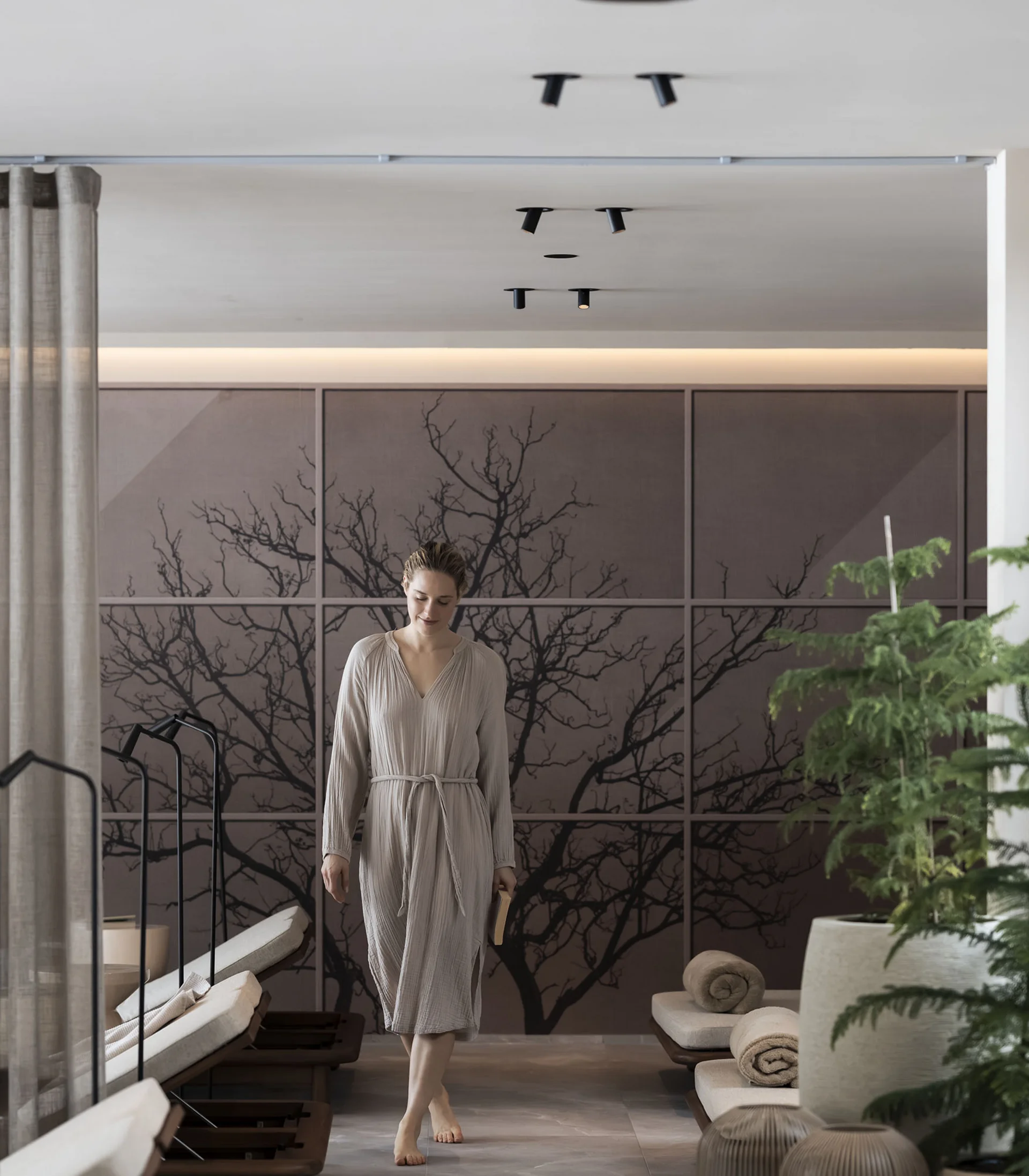 Donna in accappatoio in un'area benessere tranquilla con lettini e piante